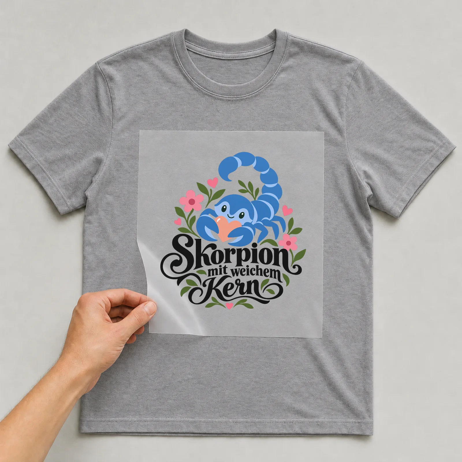 Bügelbild „Skorpion mit weichem Kern“ auf grauem T-Shirt, Folie wird aufgelegt