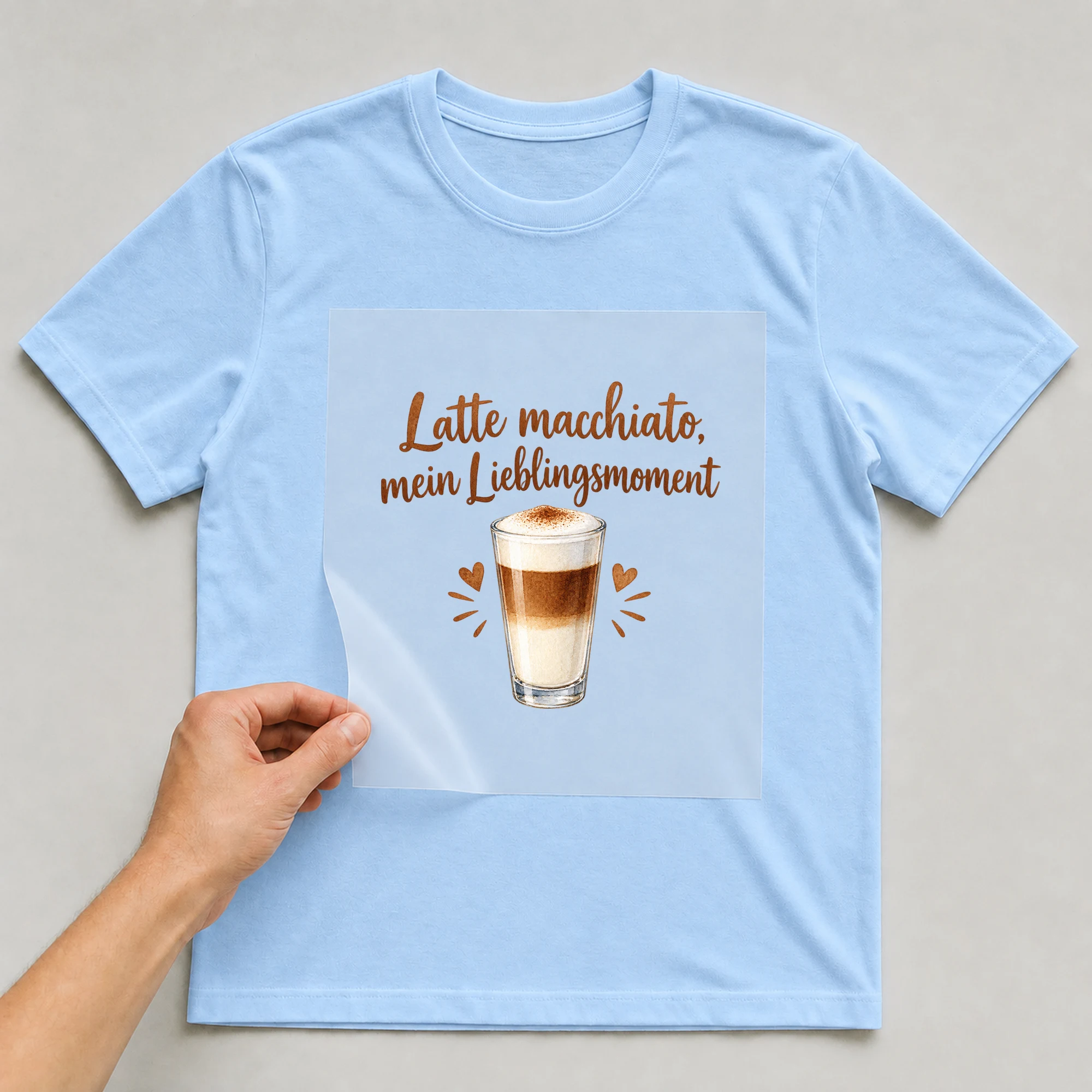 Bügelbild „Latte macchiato, mein Lieblingsmoment“ auf babyblauem T-Shirt, Folie wird aufgelegt