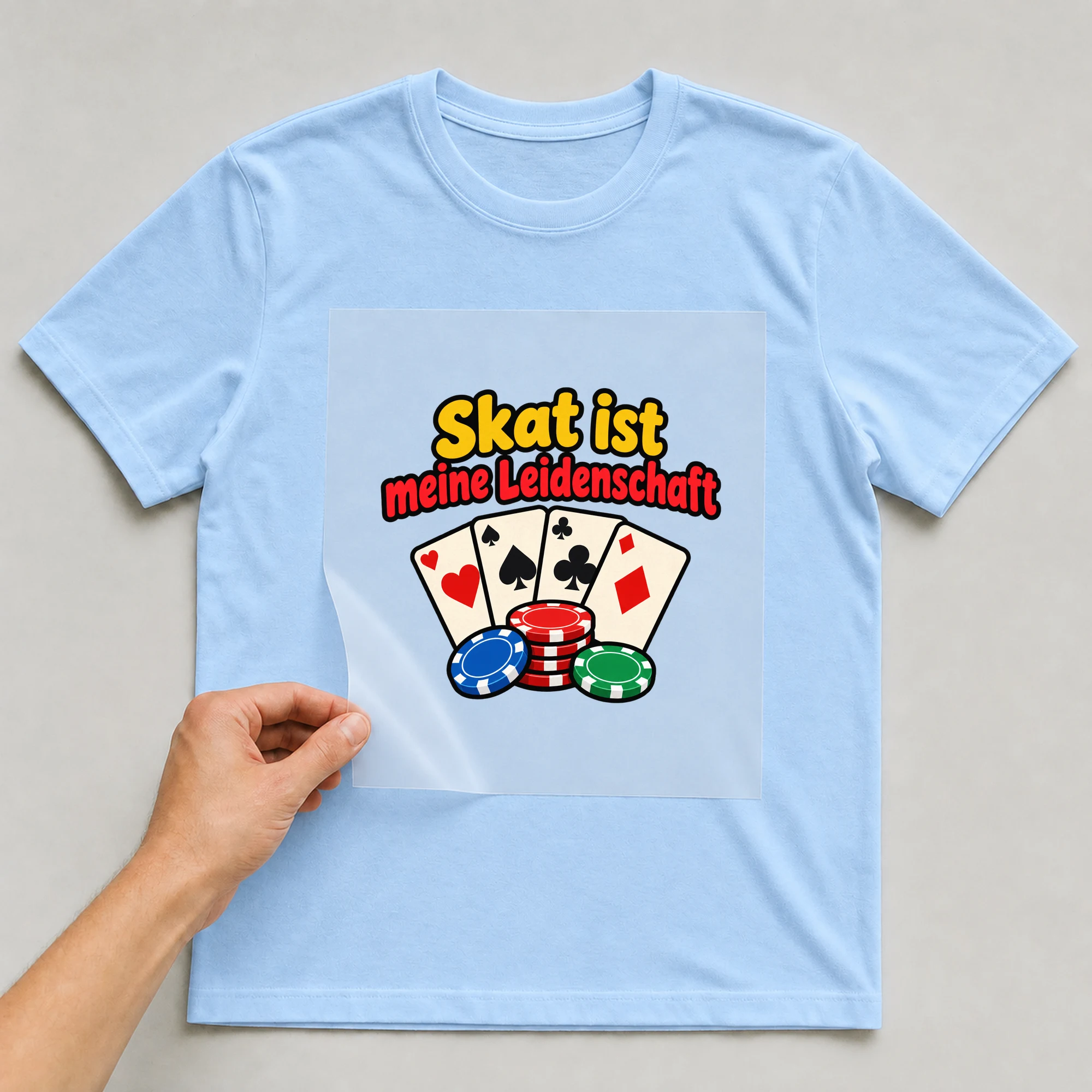 Bügelbild „Skat ist meine Leidenschaft“ auf babyblauem T-Shirt, Folie wird aufgelegt