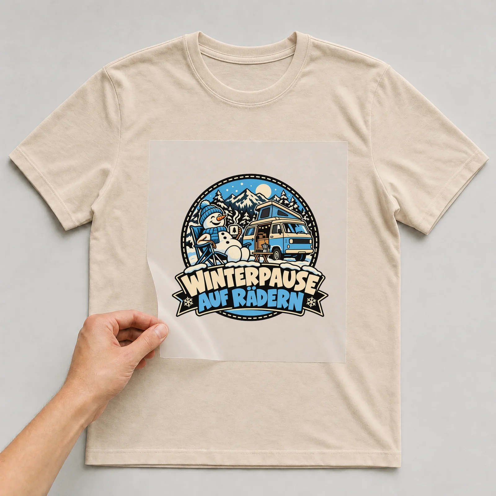 Bügelbild „Winterpause auf Rädern“ auf beigem T-Shirt, Folie wird aufgelegt