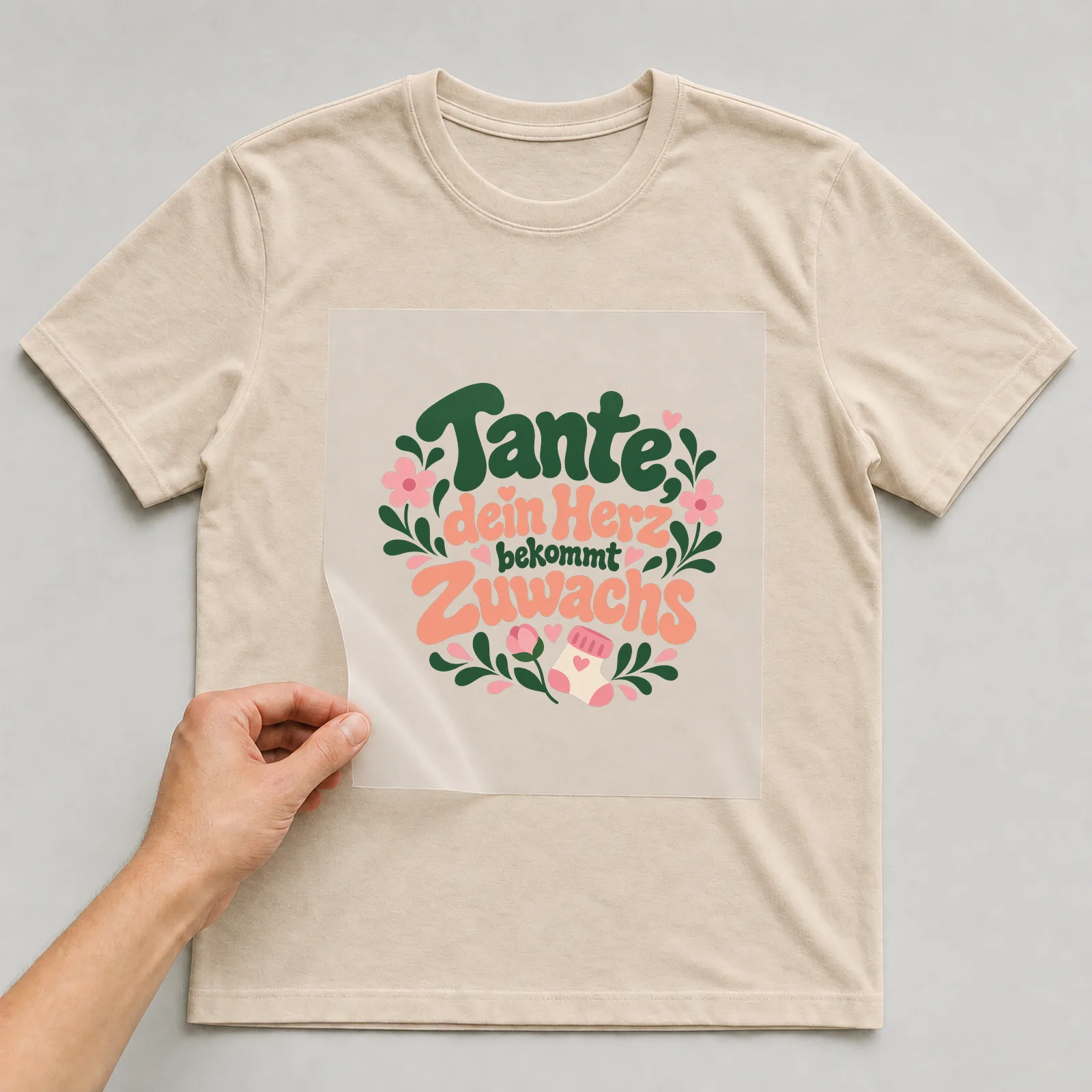 Bügelbild „Tante, dein Herz bekommt Zuwachs“ auf beigem T-Shirt, Folie wird aufgelegt