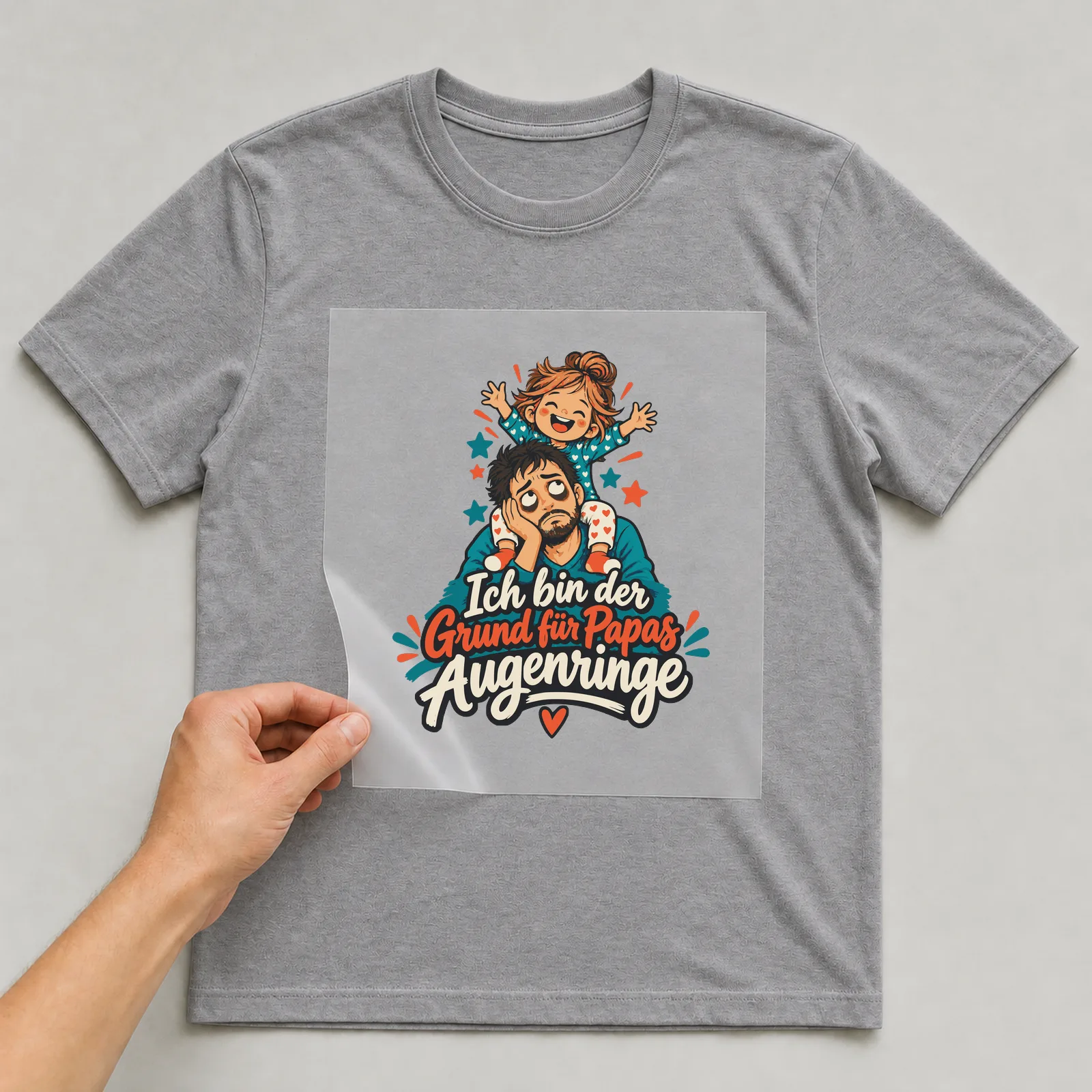 Bügelbild Ich bin der Grund für Papas Augenringe auf grauem T-Shirt, Folie wird aufgelegt