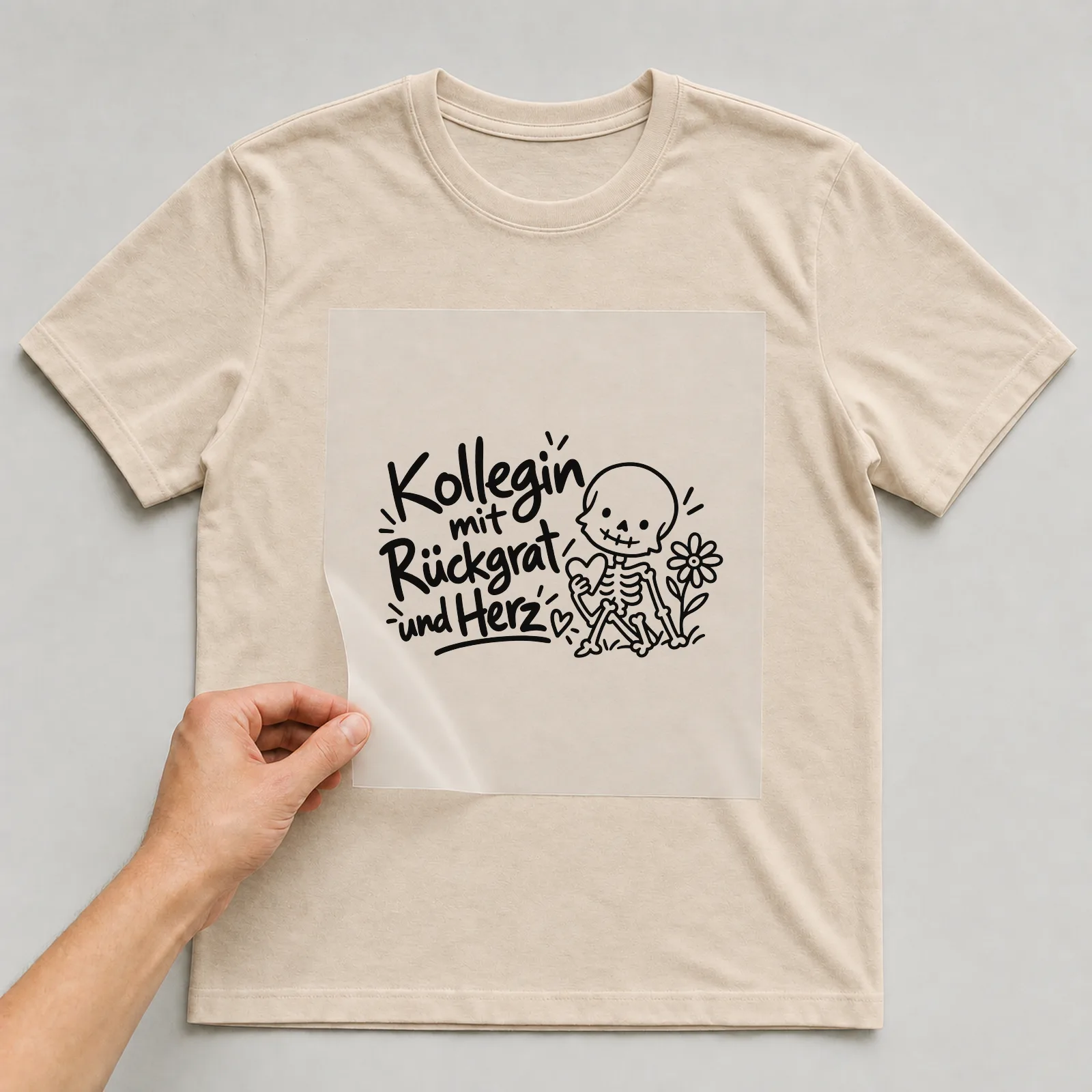 Bügelbild „Kollegin mit Rückgrat und Herz“ auf beigem T-Shirt, Folie wird aufgelegt