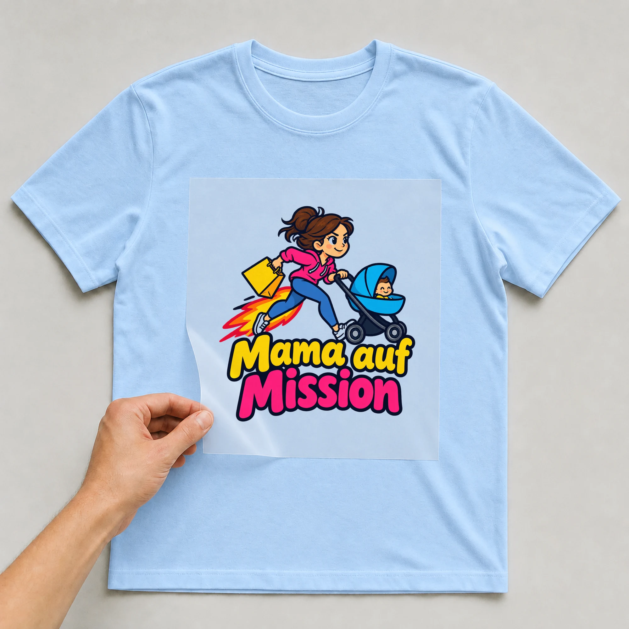 Bügelbild „Mama auf Mission“ auf babyblauem T-Shirt, Folie wird aufgelegt