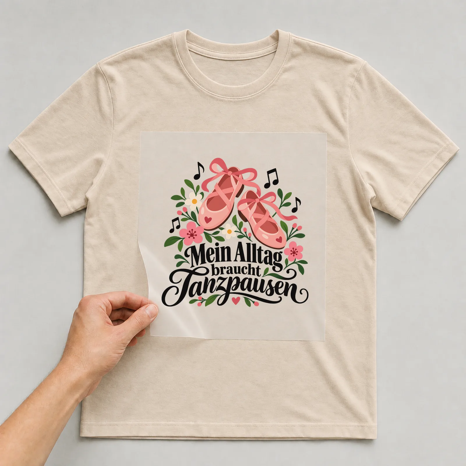 Bügelbild „Mein Alltag braucht Tanzpausen“ auf beigem T-Shirt, Folie wird aufgelegt