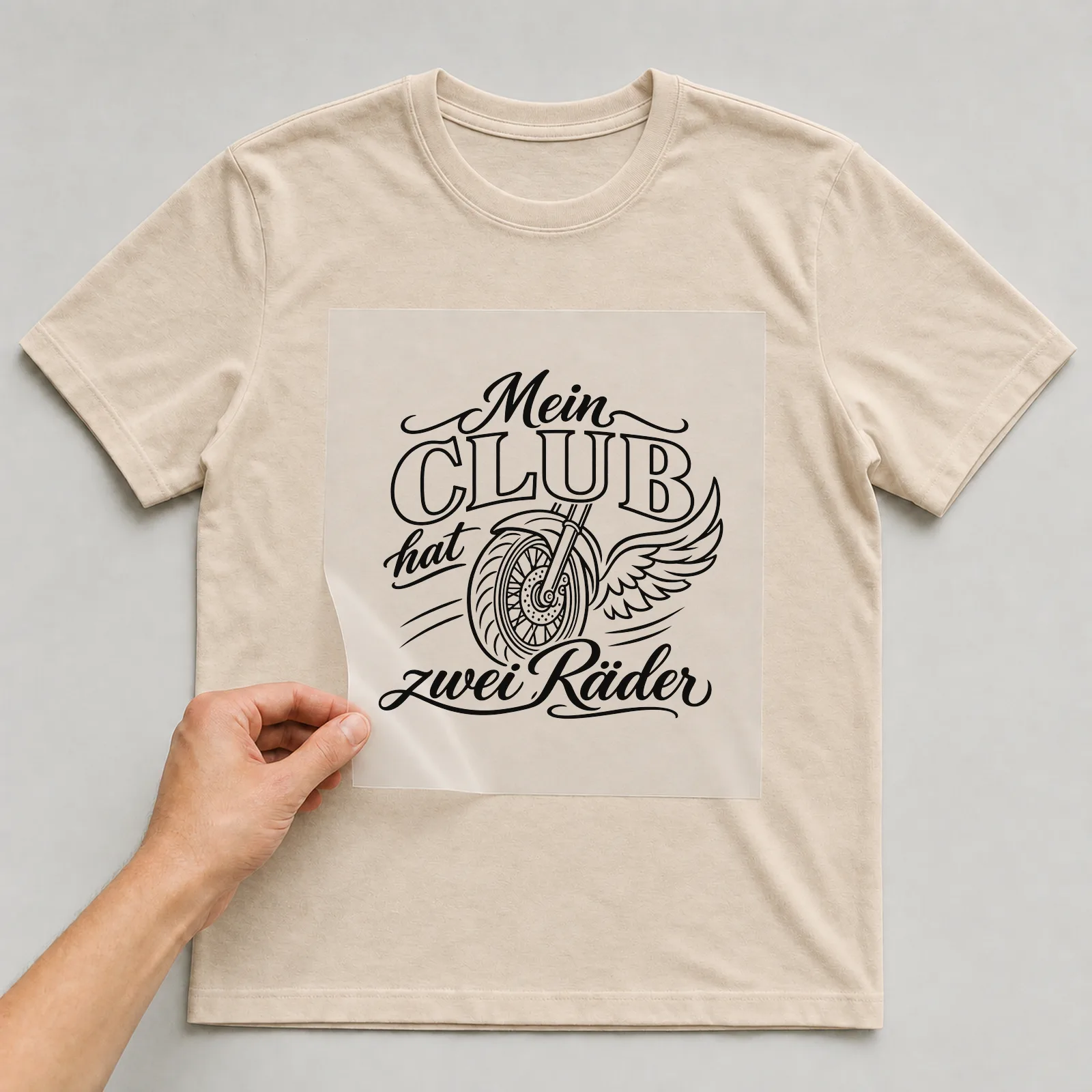 Bügelbild „Mein Club hat zwei Räder“ auf beigem T-Shirt, Folie wird aufgelegt