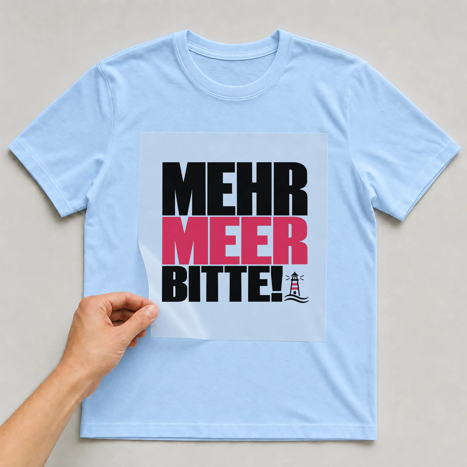Bügelbild „Mehr Meer bitte!“ auf hellblauem T-Shirt, Folie wird aufgelegt