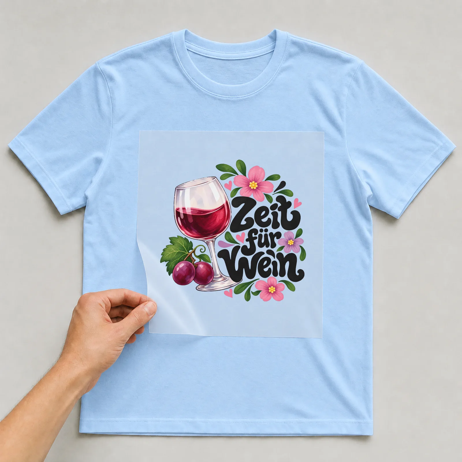 Bügelbild „Zeit für Wein!“ auf hellblauem T-Shirt, Folie wird aufgelegt
