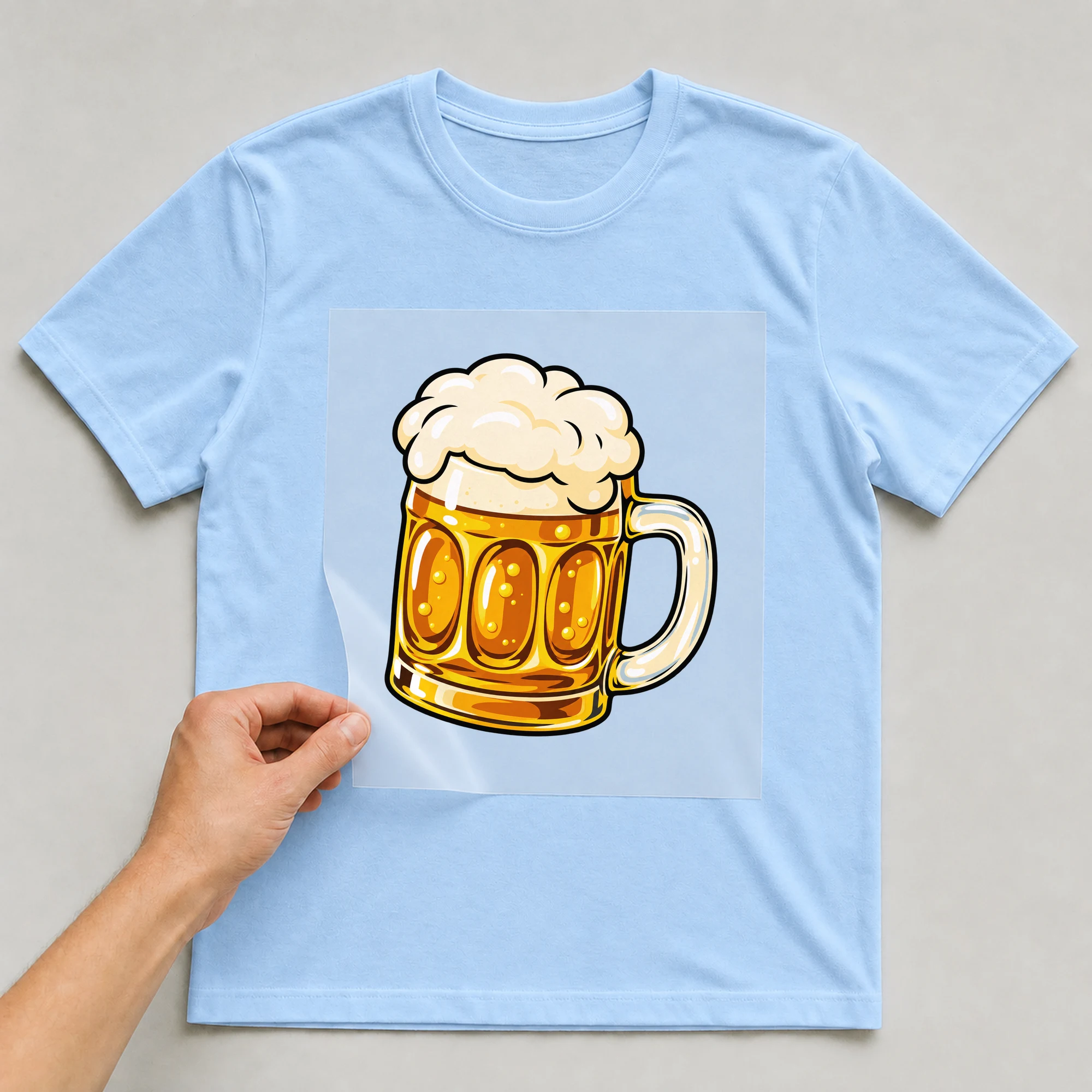 Bügelbild „Maßkrug Bier“ auf babyblauem T-Shirt, Folie wird aufgelegt
