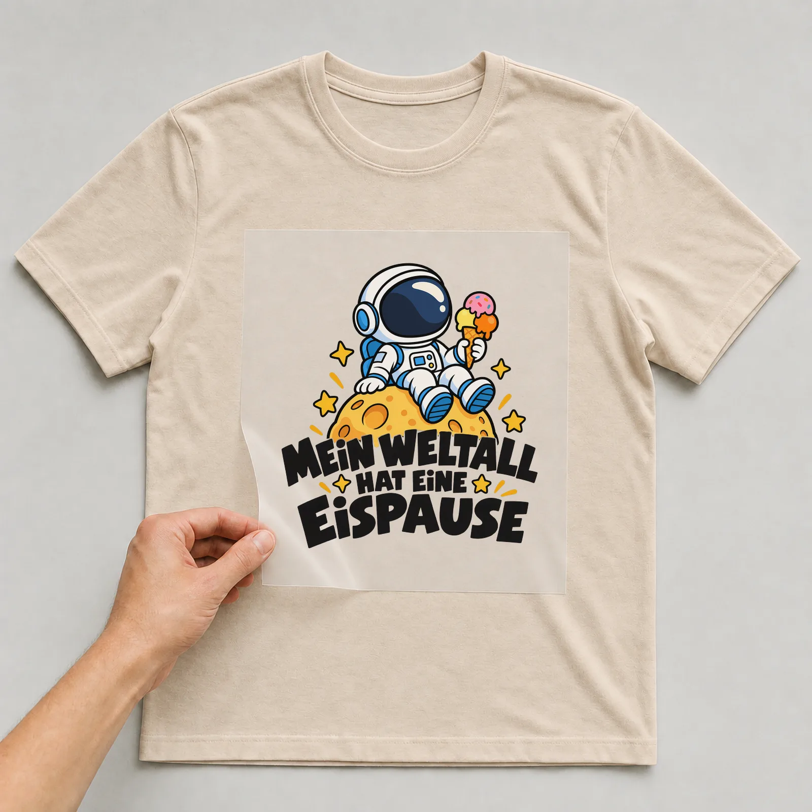 Bügelbild „Mein Weltall hat eine Eispause“ auf beigem T-Shirt, Folie wird aufgelegt