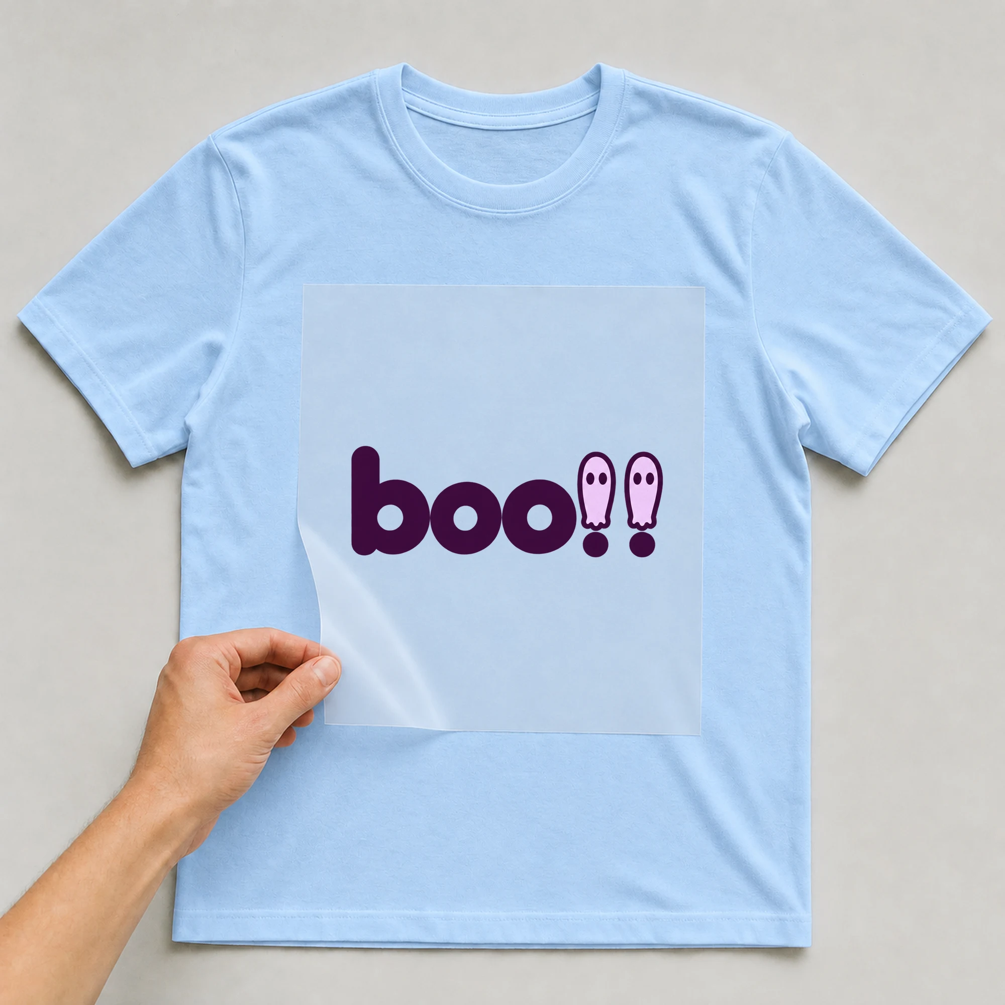 Bügelbild „boo!!“ auf babyblauem T-Shirt, Folie wird aufgelegt
