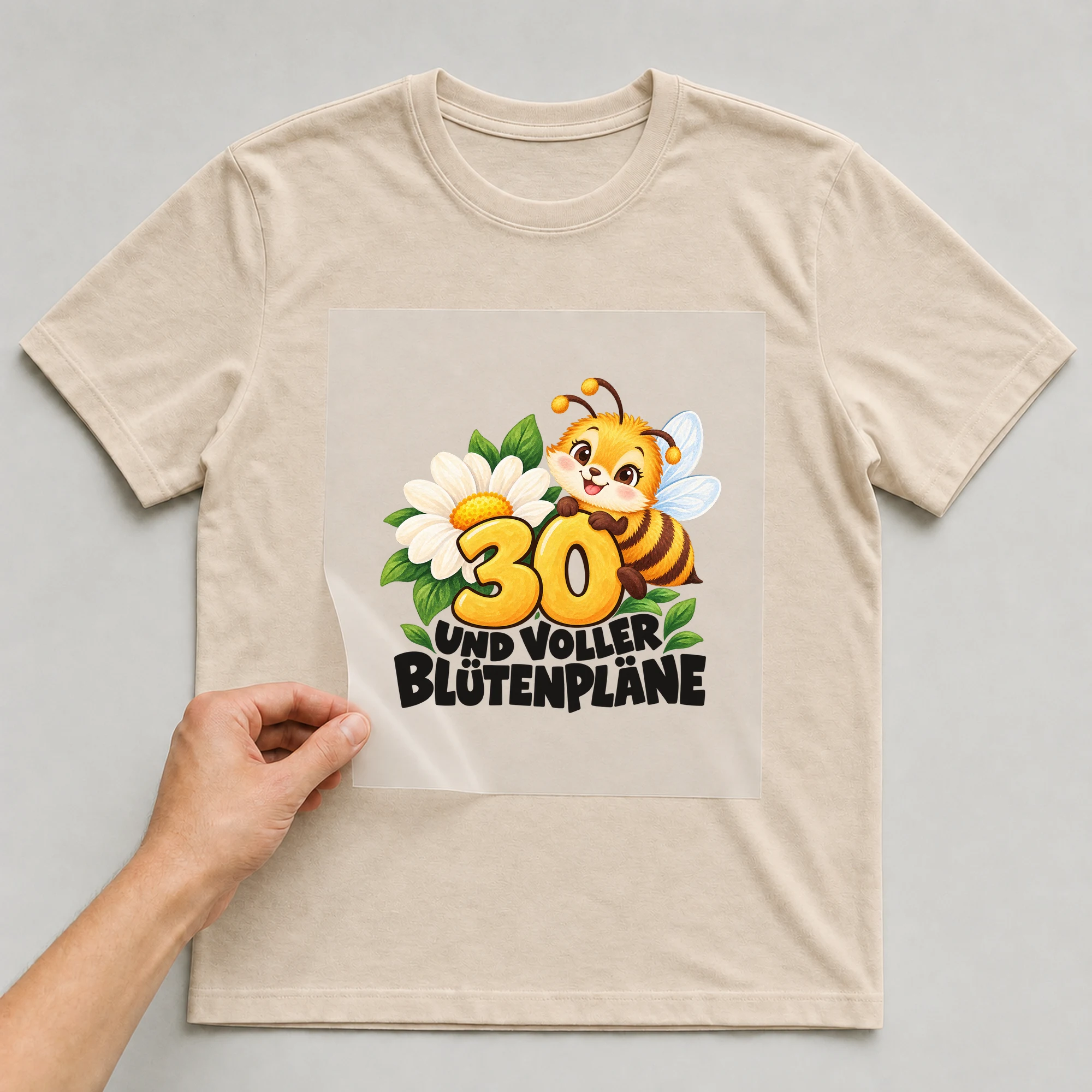 Bügelbild „30 Und voller Blütenpläne“ auf beigem T-Shirt, Folie wird aufgelegt
