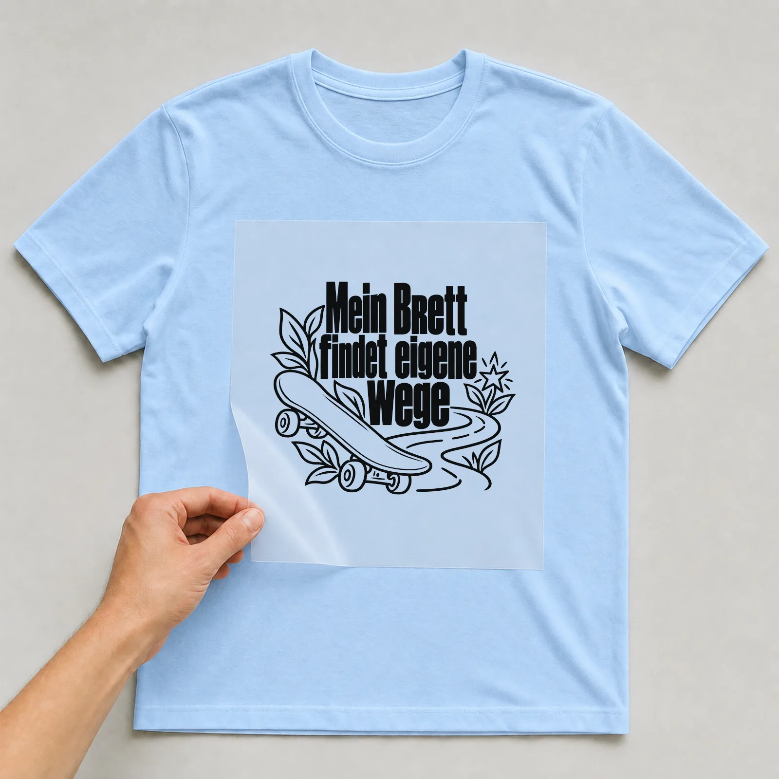 Bügelbild „Mein Brett findet eigene Wege“ auf hellblauem T-Shirt, Folie wird aufgelegt