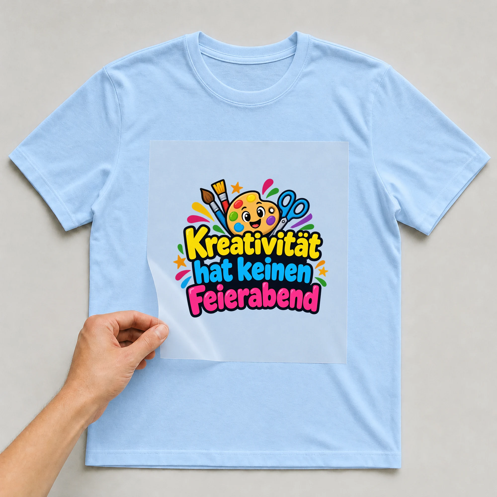 Bügelbild „Kreativität hat keinen Feierabend“ auf babyblauem T-Shirt, Folie wird aufgelegt