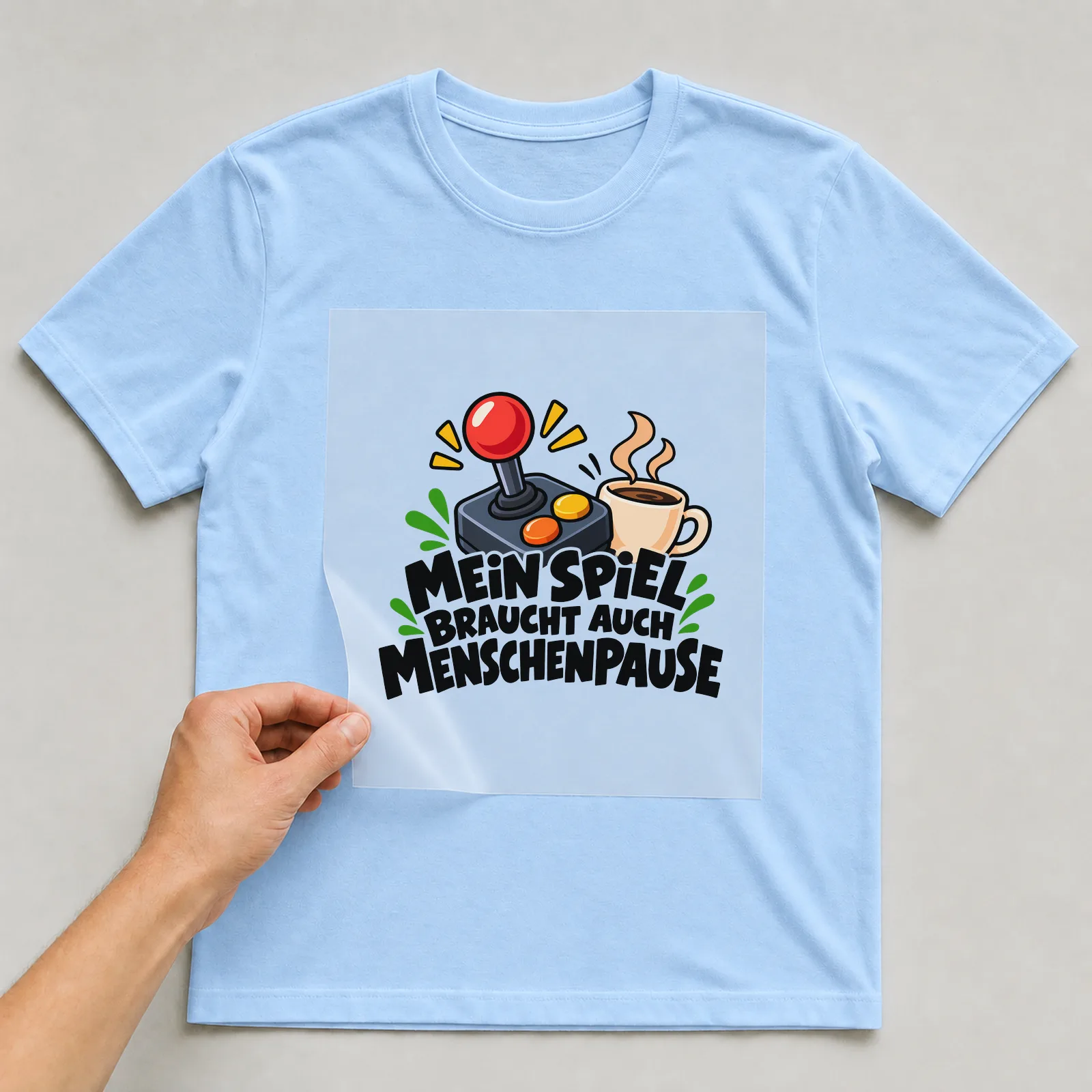 Bügelbild „Mein spiel braucht auch Menschenpause“ auf hellblauem T-Shirt, Folie wird aufgelegt