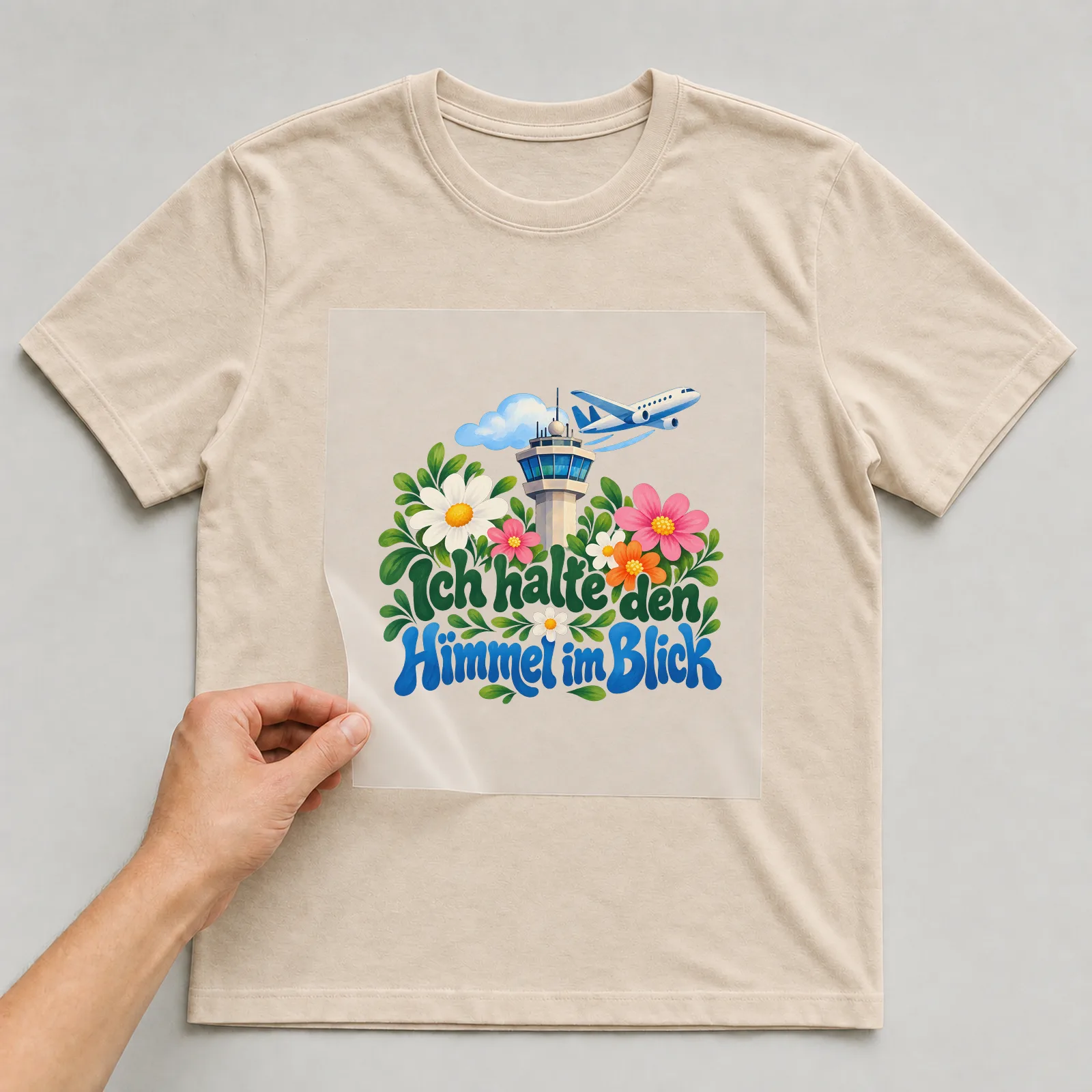Bügelbild „Ich halte den Himmel im Blick“ auf beigem T-Shirt, Folie wird aufgelegt