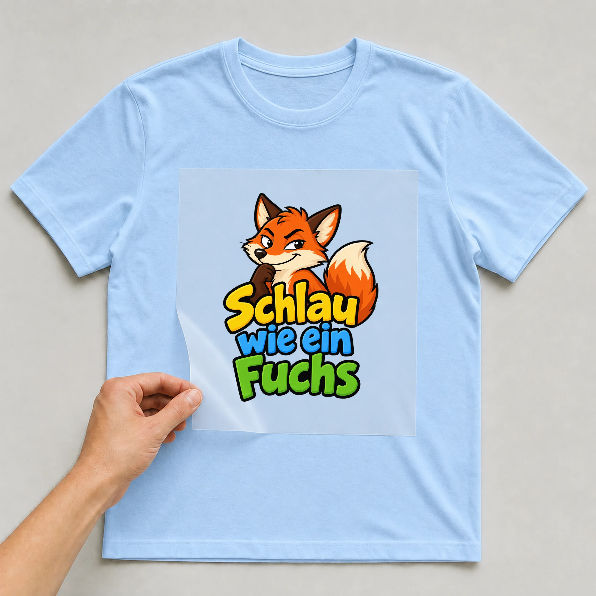 Bügelbild „Schlau wie ein Fuchs“ auf babyblauem T-Shirt, Folie wird aufgelegt
