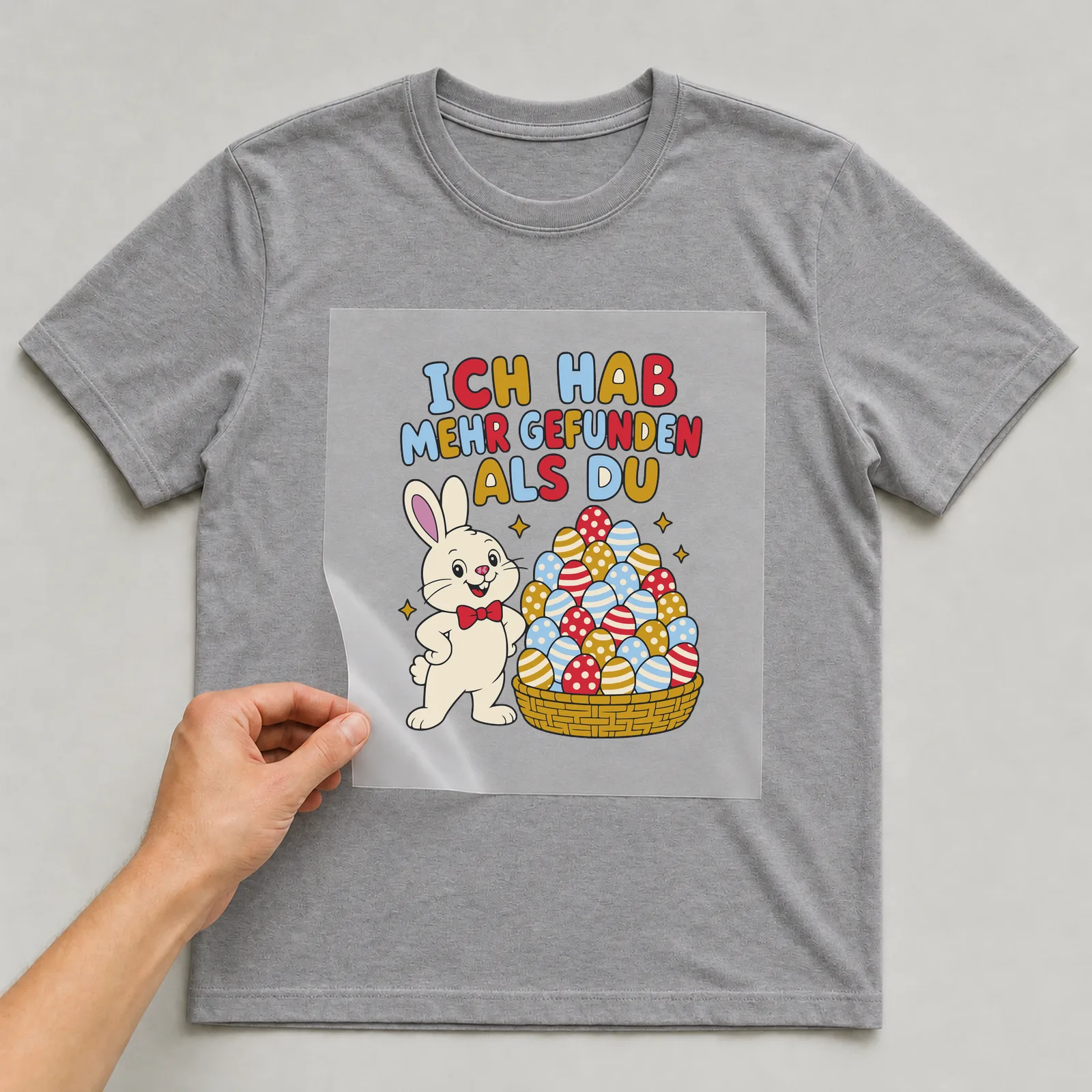 Bügelbild Ich hab mehr gefunden als du auf grauem T-Shirt, Folie wird aufgelegt