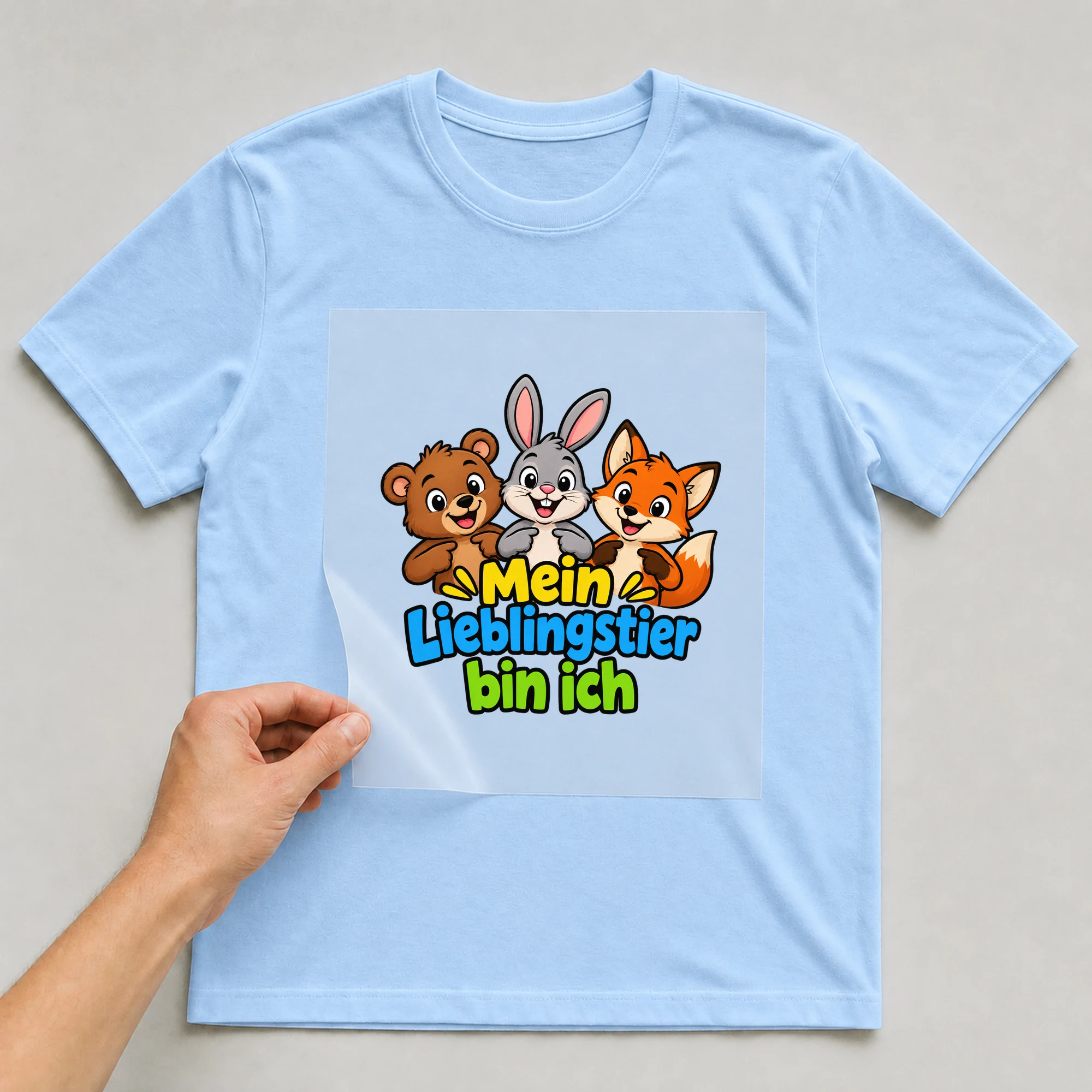 Bügelbild „Mein Lieblingstier bin ich“ auf babyblauem T-Shirt, Folie wird aufgelegt