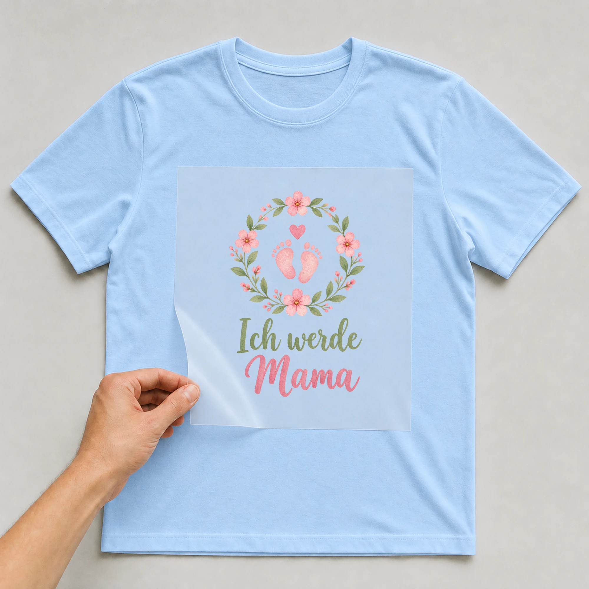 Bügelbild „Ich werde Mama“ auf babyblauem T-Shirt, Folie wird aufgelegt
