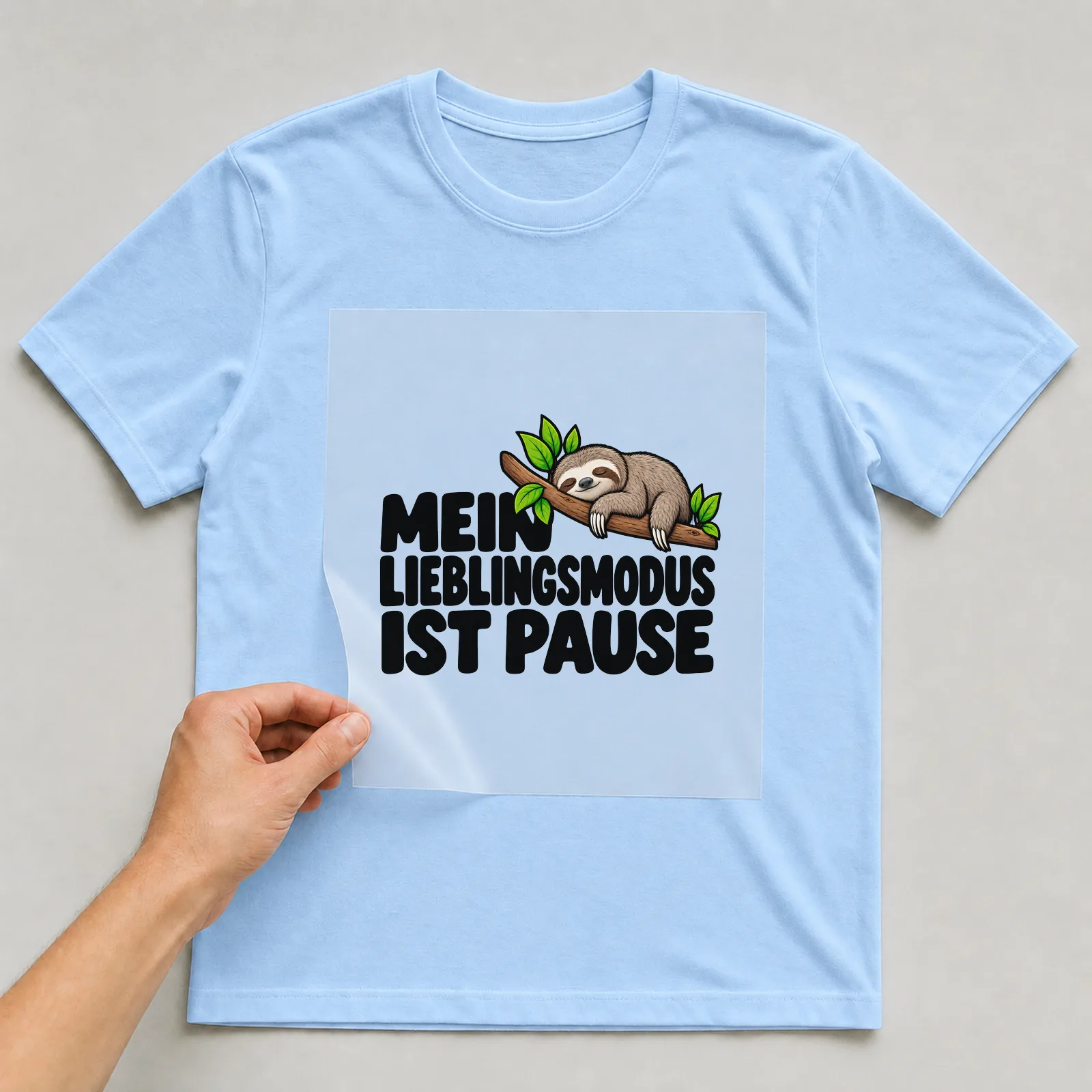 Bügelbild „Mein Lieblingsmodus ist Pause“ auf hellblauem T-Shirt, Folie wird aufgelegt