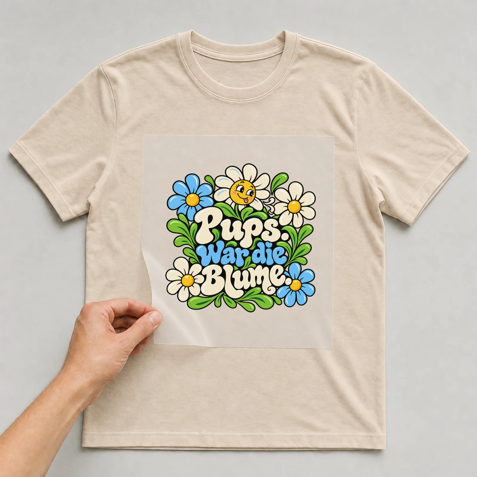 Bügelbild „Pups. War die Blume.“ auf beigem T-Shirt, Folie wird aufgelegt