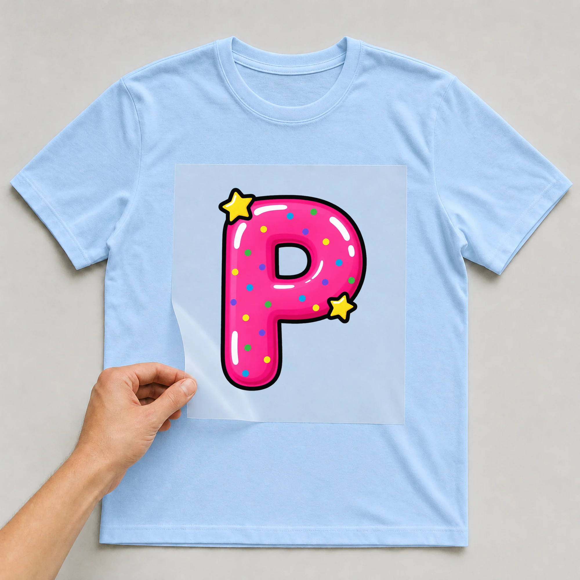 Bügelbild „Buchstabe P im Comic-Ballon-Stil“ auf babyblauem T-Shirt, Folie wird aufgelegt