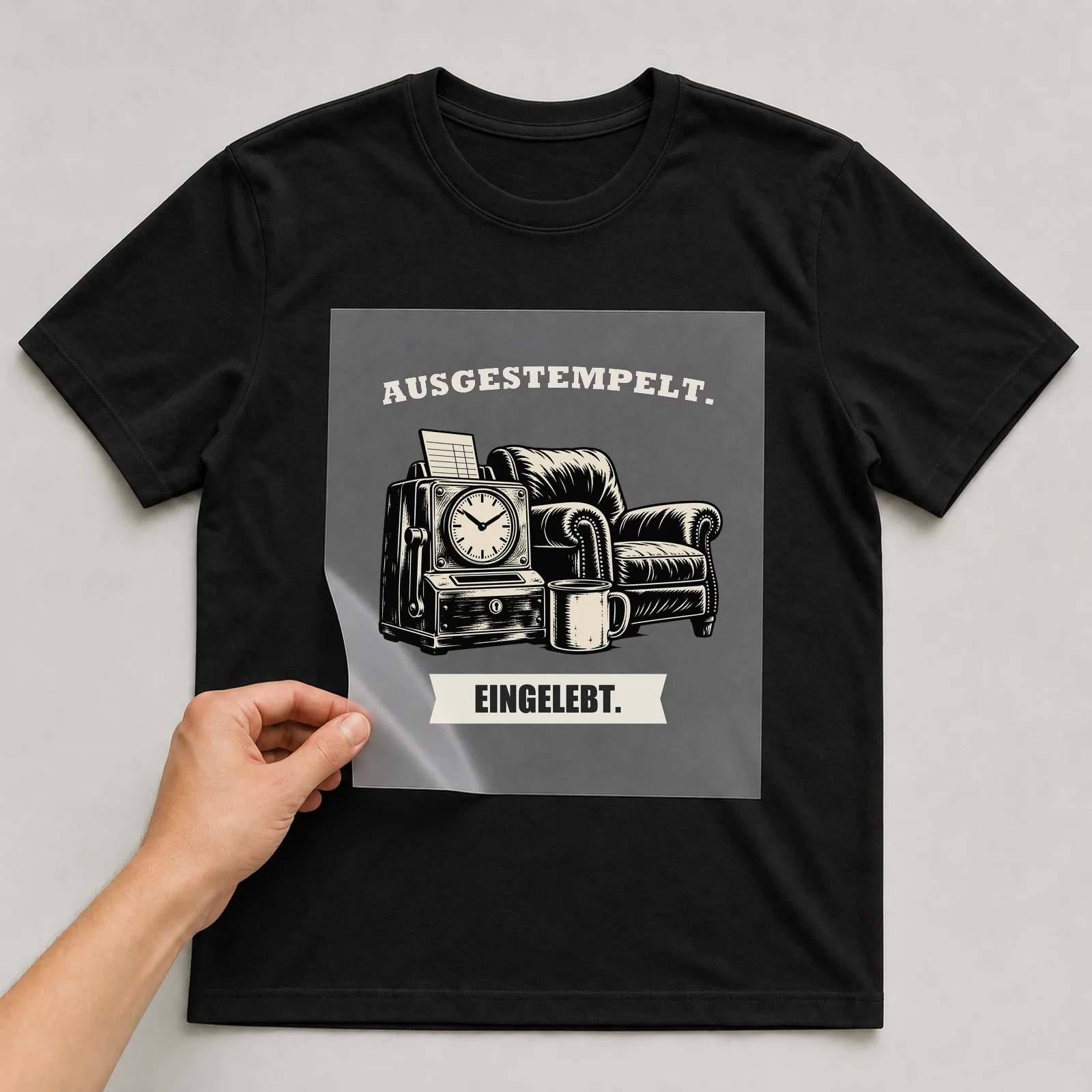 Bügelbild „Ausgestempelt. Eingelebt.“ auf schwarzem T-Shirt, Folie wird aufgelegt