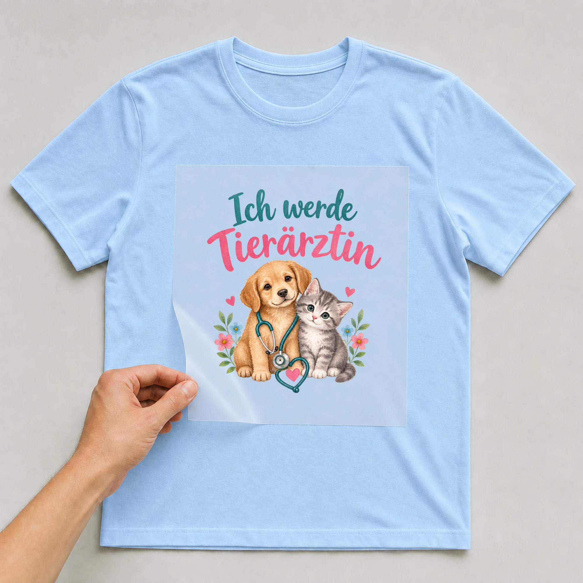 Bügelbild „Ich werde Tierärztin“ auf babyblauem T-Shirt, Folie wird aufgelegt