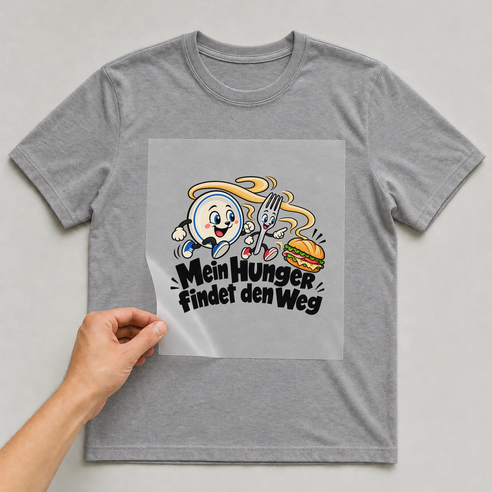 Bügelbild „Mein Hunger findet den Weg“ auf grauem T-Shirt, Folie wird aufgelegt