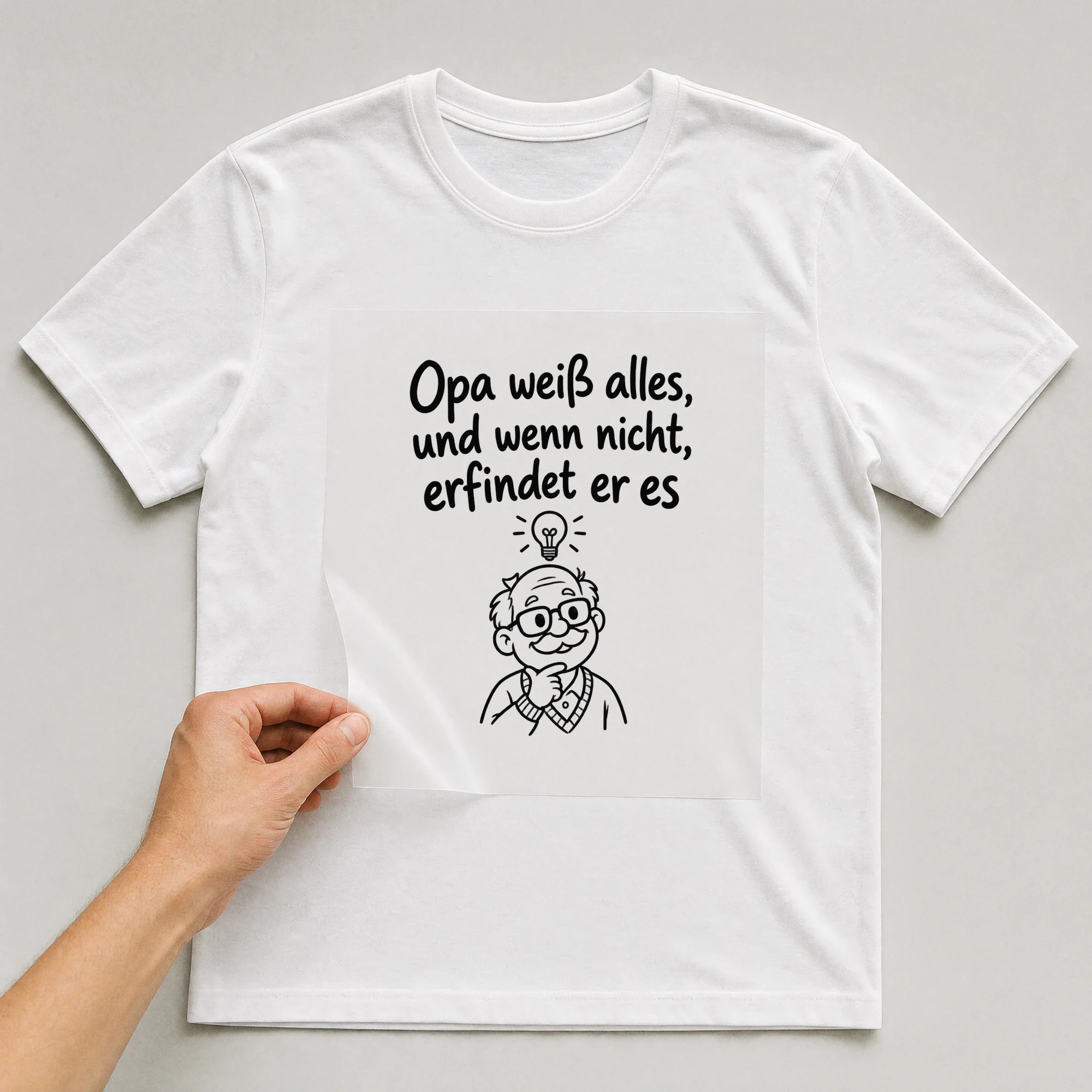 Bügelbild „Opa weiß alles, und wenn nicht, erfindet er es“ auf weißem T-Shirt, Folie wird aufgelegt