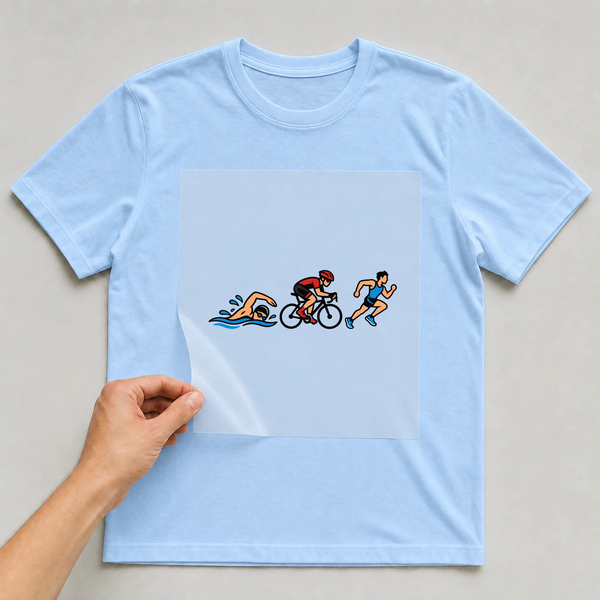 Bügelbild „Triathlon“ auf babyblauem T-Shirt, Folie wird aufgelegt