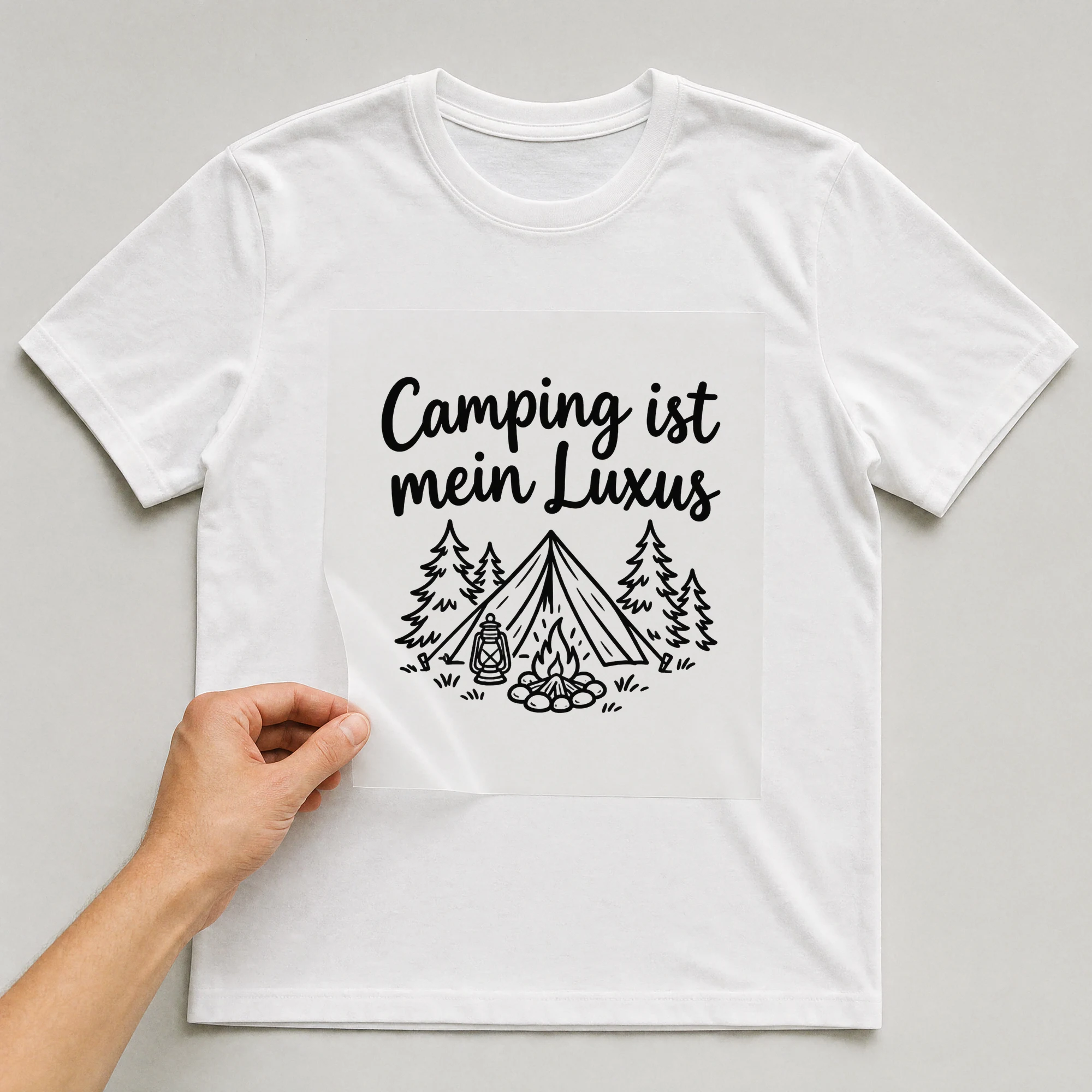 Bügelbild „Camping ist mein Luxus“ auf weißem T-Shirt, Folie wird aufgelegt