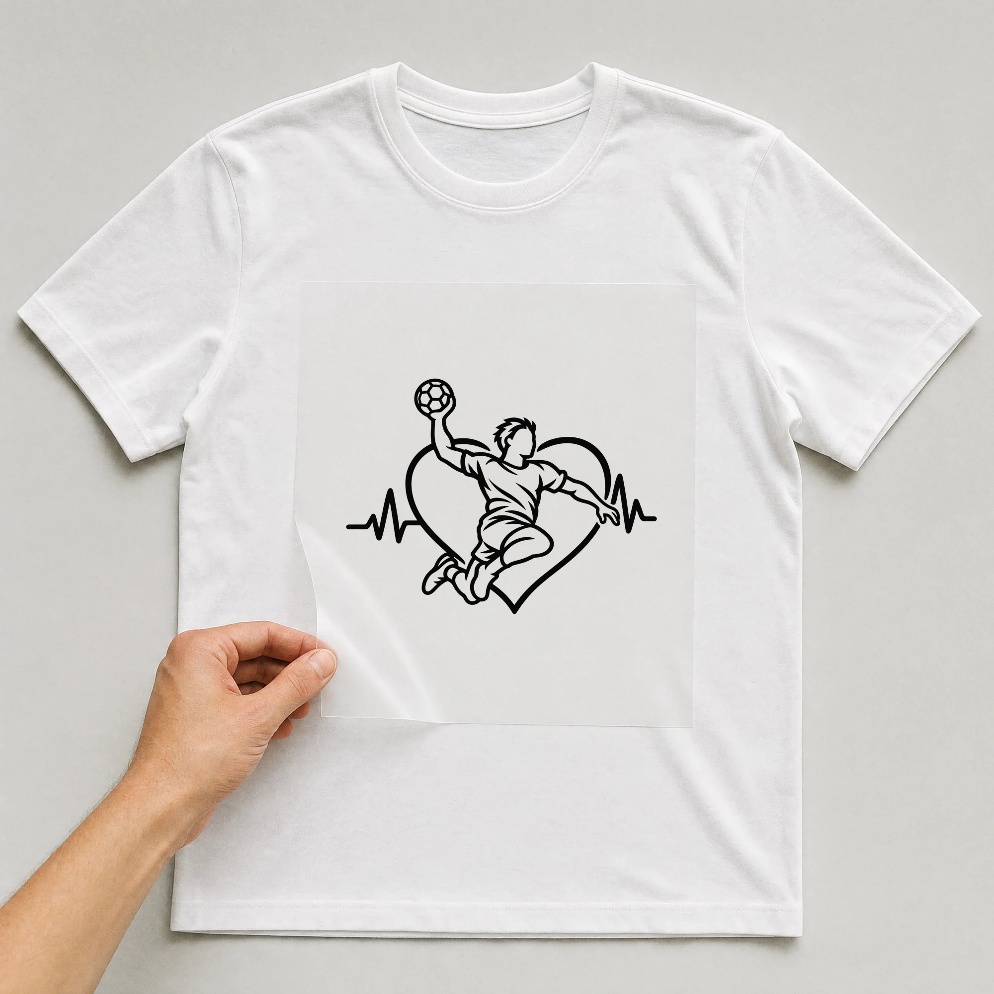 Bügelbild „Herzschlag Handball“ auf weißem T-Shirt, Folie wird aufgelegt