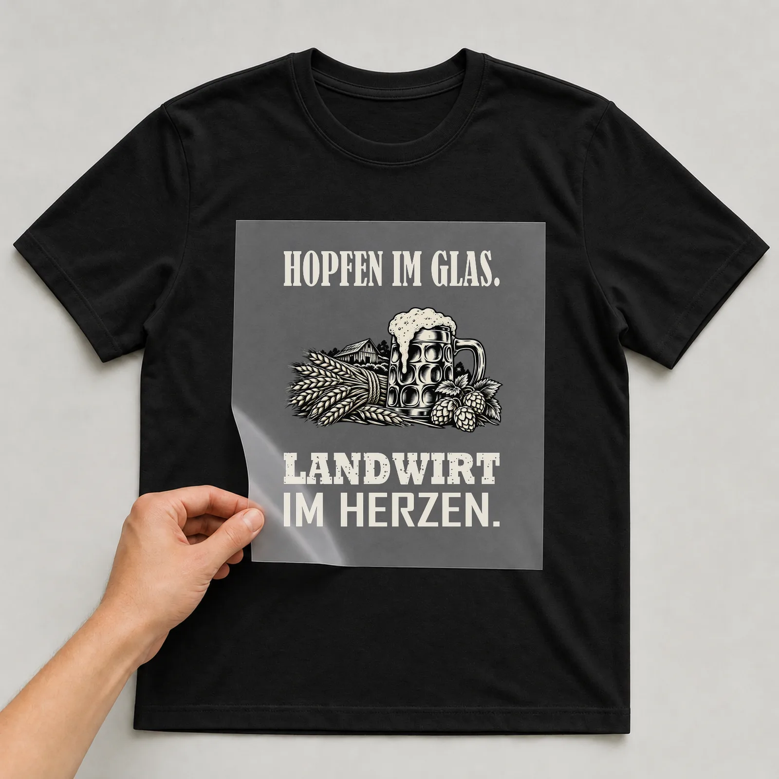 Bügelbild „Hopfen im Glas. Landwirt im Herzen.“ auf schwarzem T-Shirt, Folie wird aufgelegt