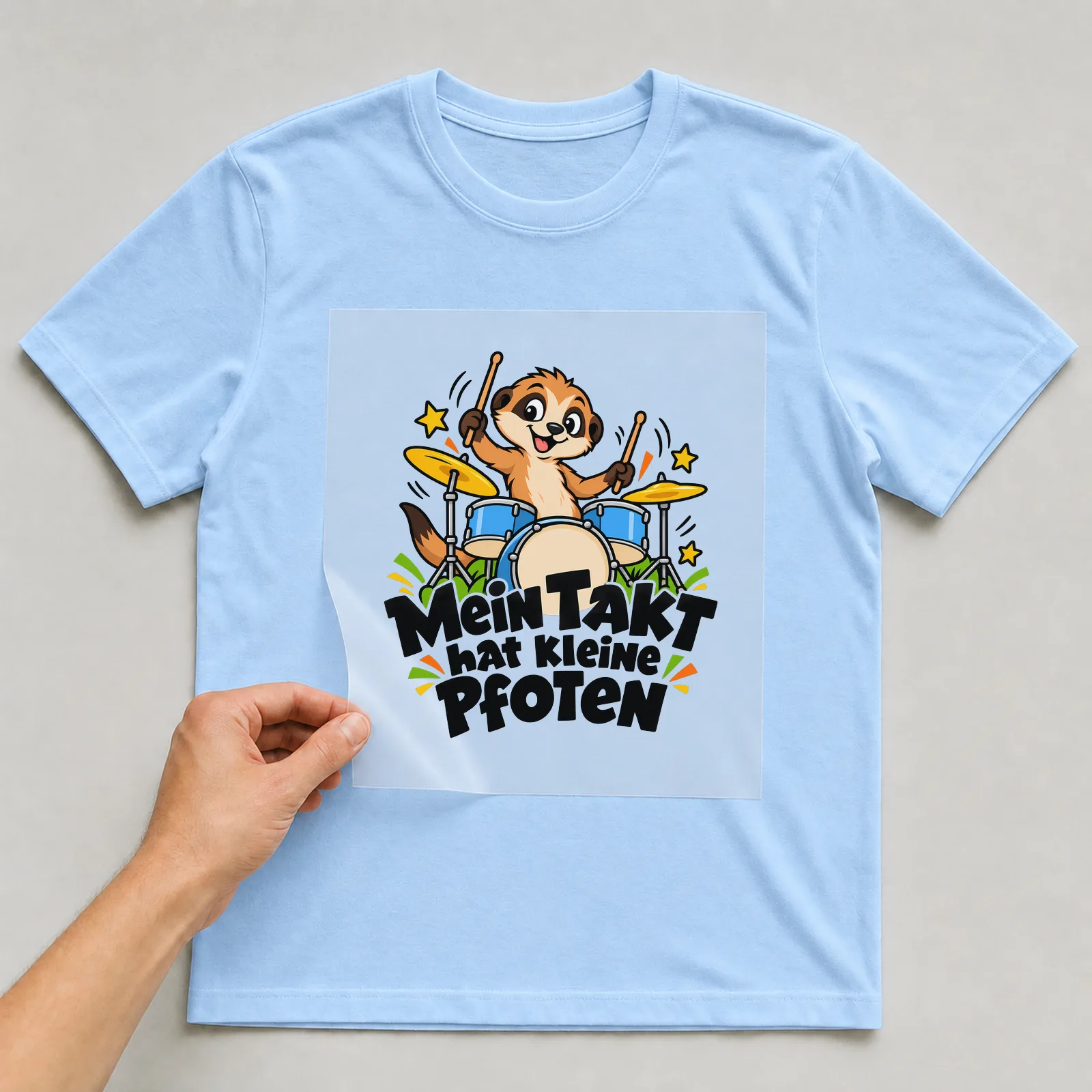 Bügelbild „Mein Takt hat kleine Pfoten“ auf hellblauem T-Shirt, Folie wird aufgelegt