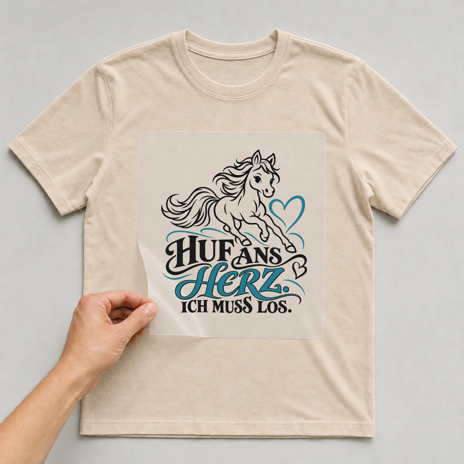 Bügelbild „Huf ans Herz. Ich muss los.“ auf beigem T-Shirt, Folie wird aufgelegt