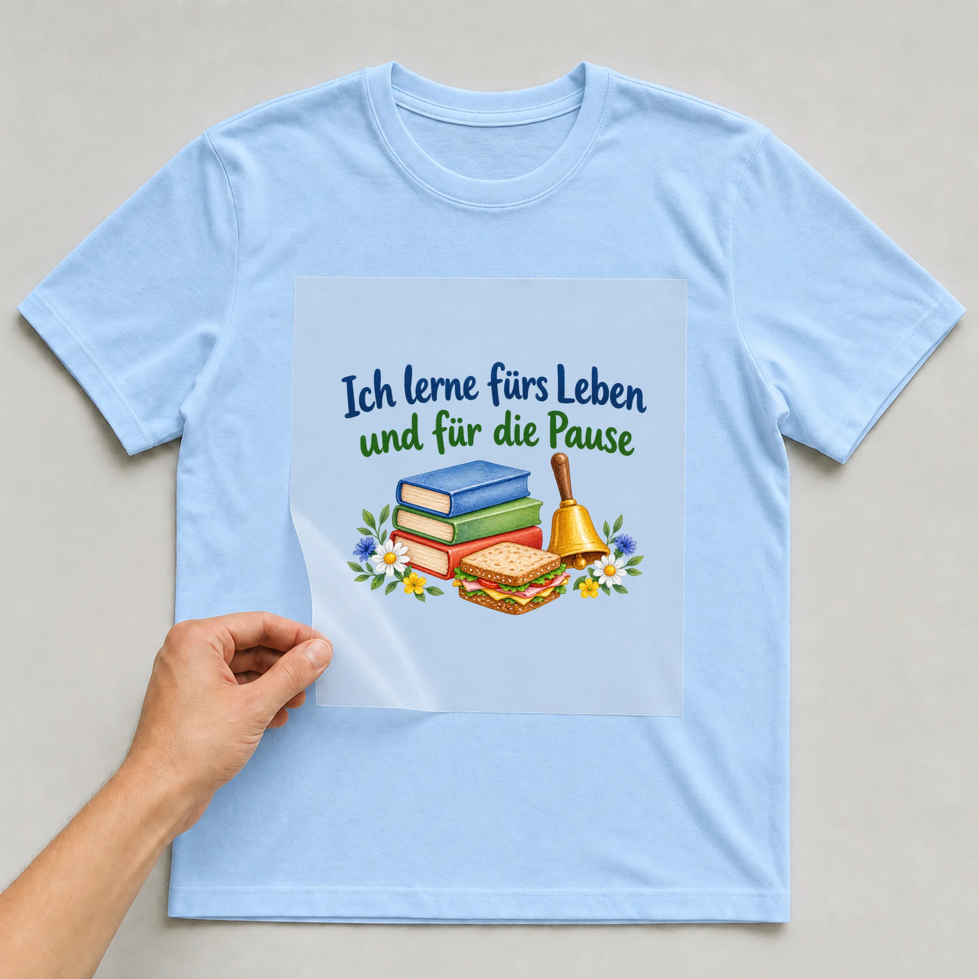 Bügelbild „Ich lerne fürs Leben und für die Pause“ auf babyblauem T-Shirt, Folie wird aufgelegt
