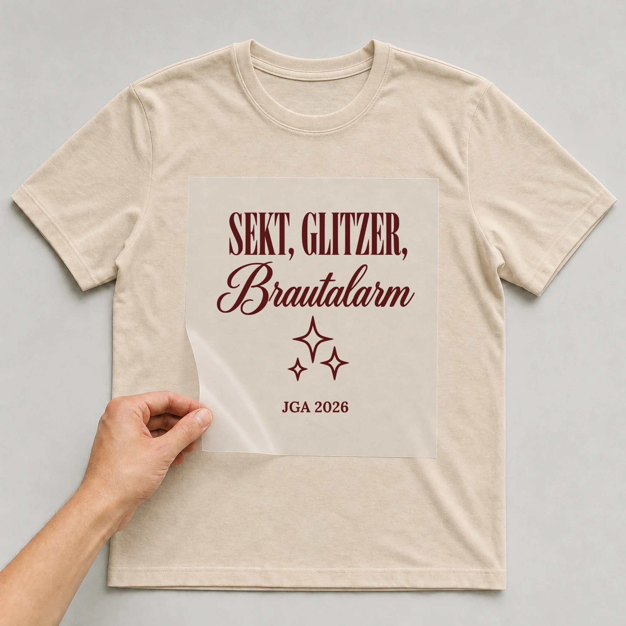 Bügelbild Sekt, Glitzer, Brautalarm auf beigem T-Shirt, Folie wird aufgelegt