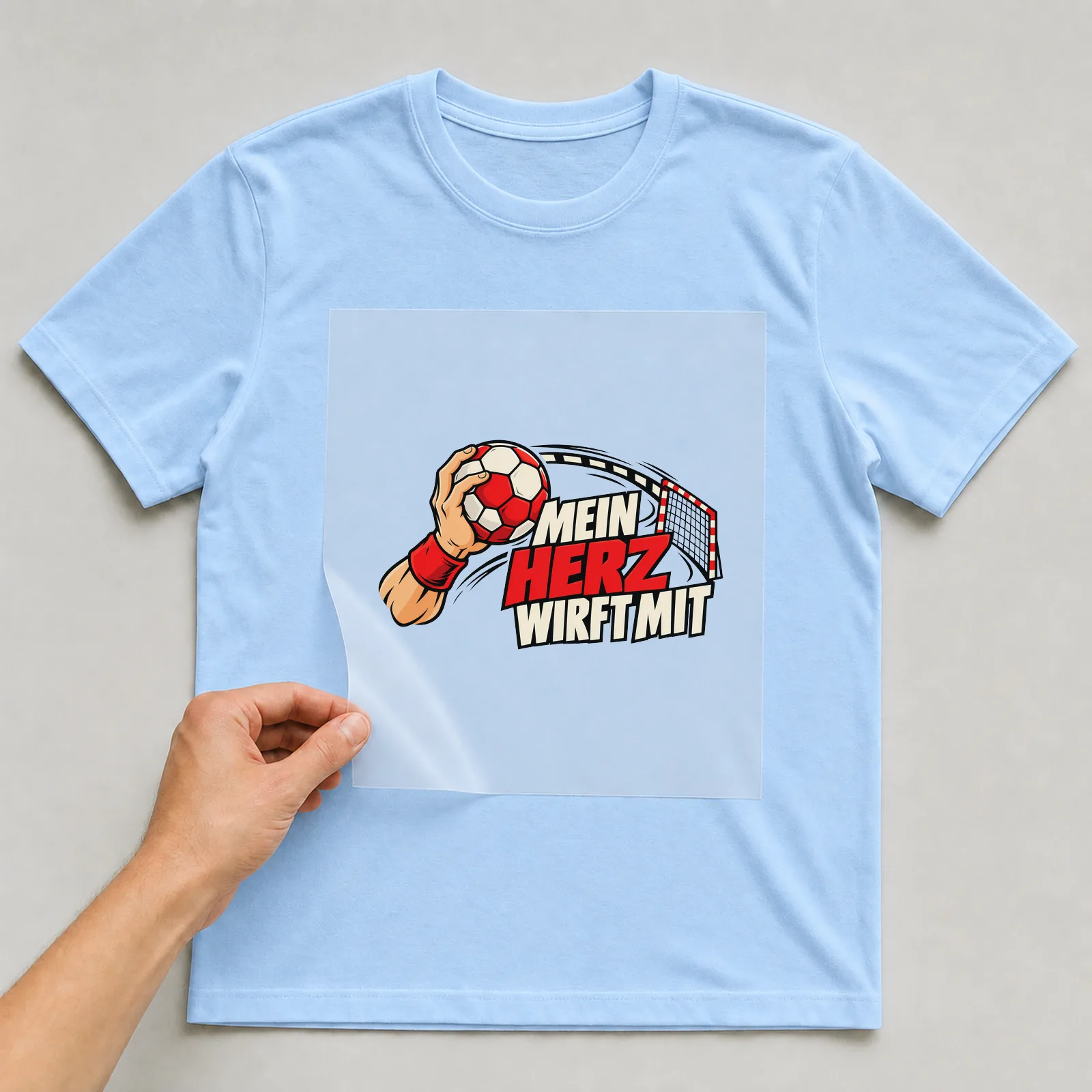 Bügelbild „Mein Herz wirft mit“ auf hellblauem T-Shirt, Folie wird aufgelegt