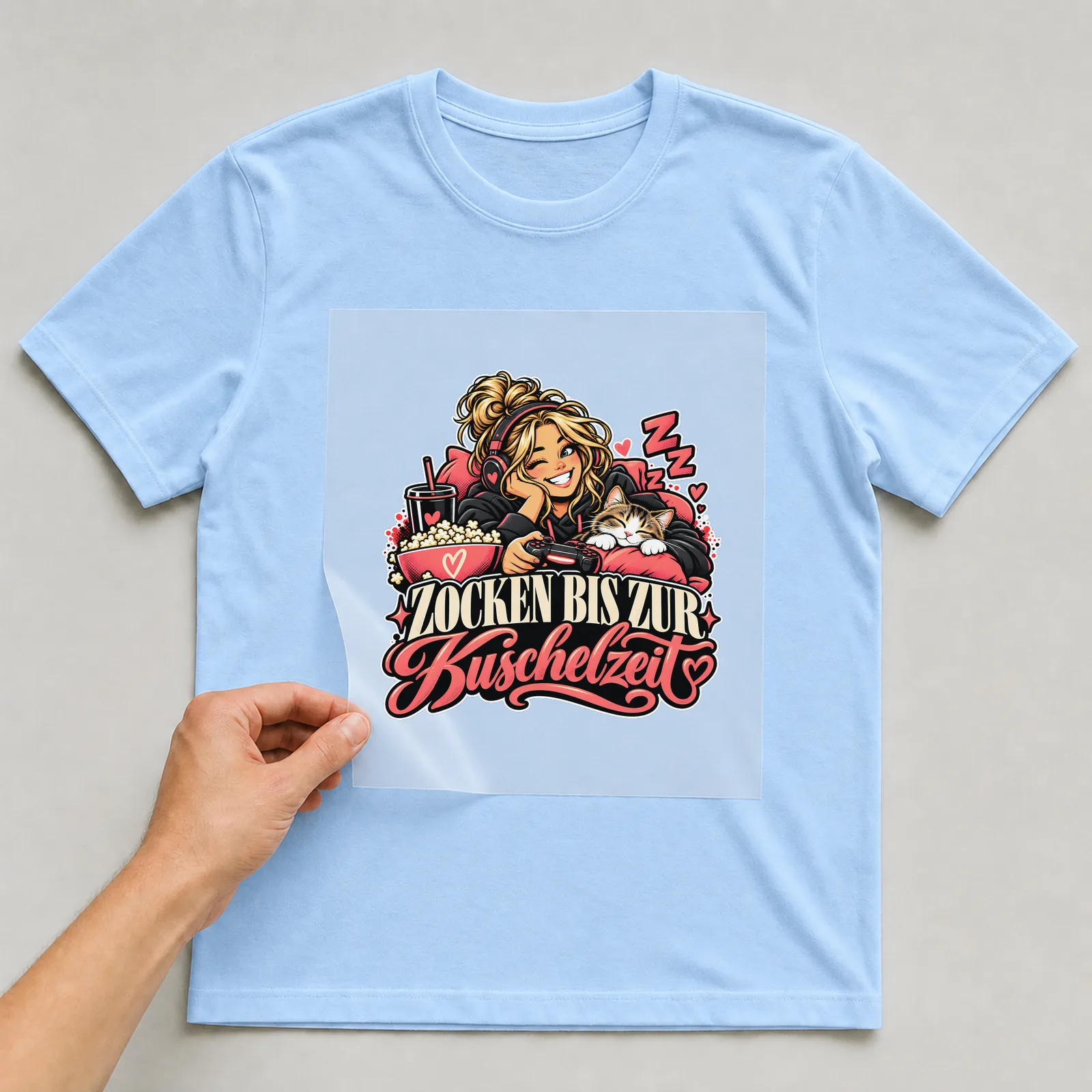 Bügelbild „Zocken bis zur Kuschelzeit“ auf hellblauem T-Shirt, Folie wird aufgelegt