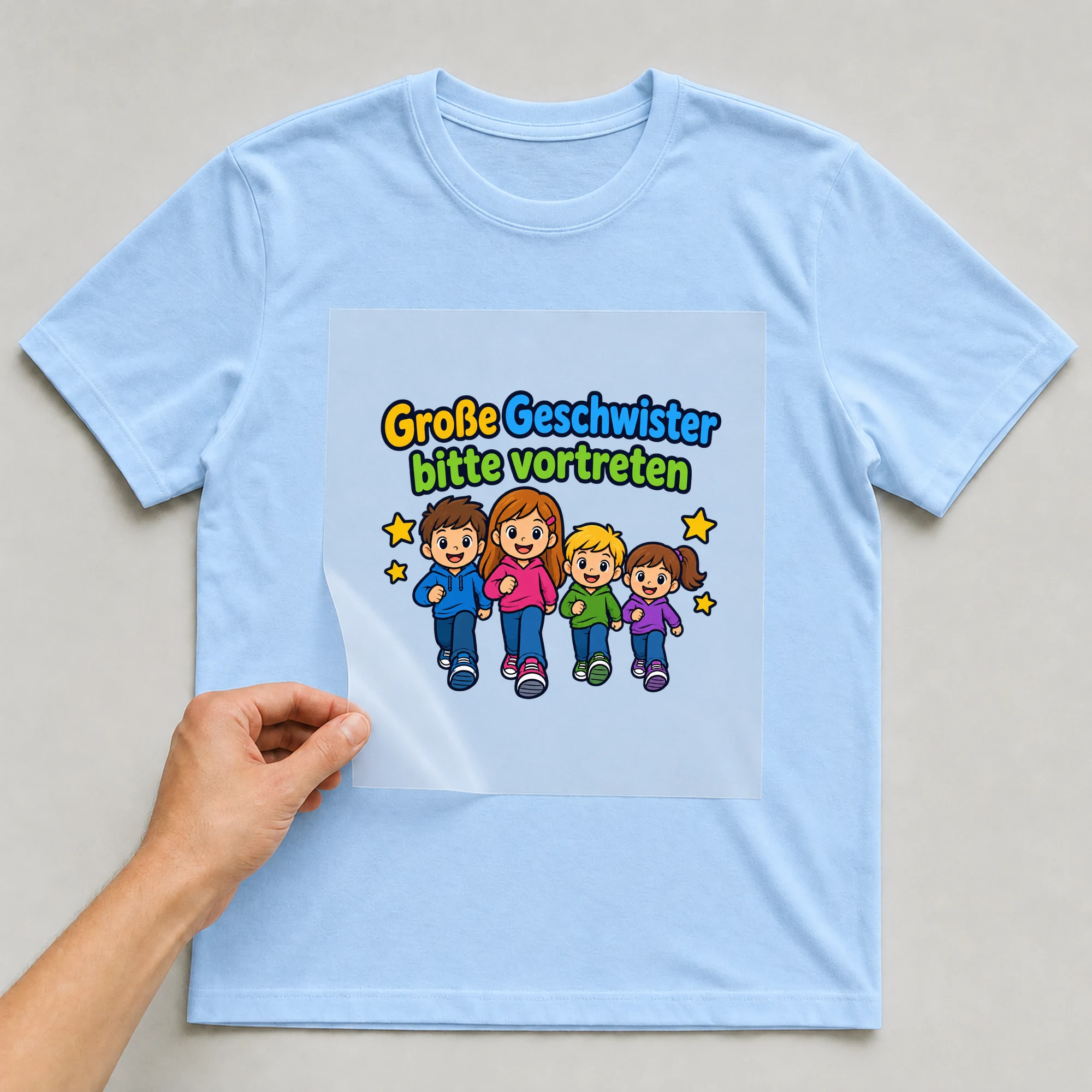 Bügelbild „Große Geschwister bitte vortreten“ auf babyblauem T-Shirt, Folie wird aufgelegt