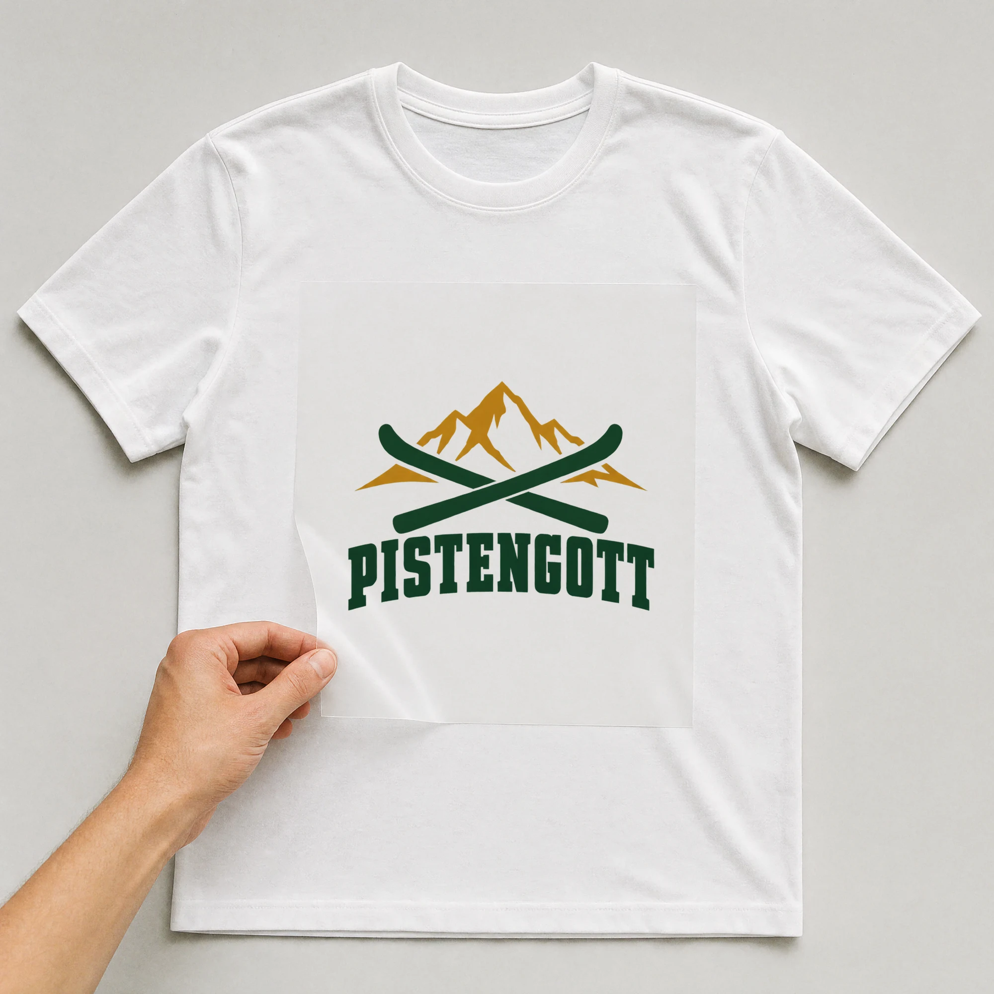 Bügelbild „Pistengott“ auf weißem T-Shirt, Folie wird aufgelegt