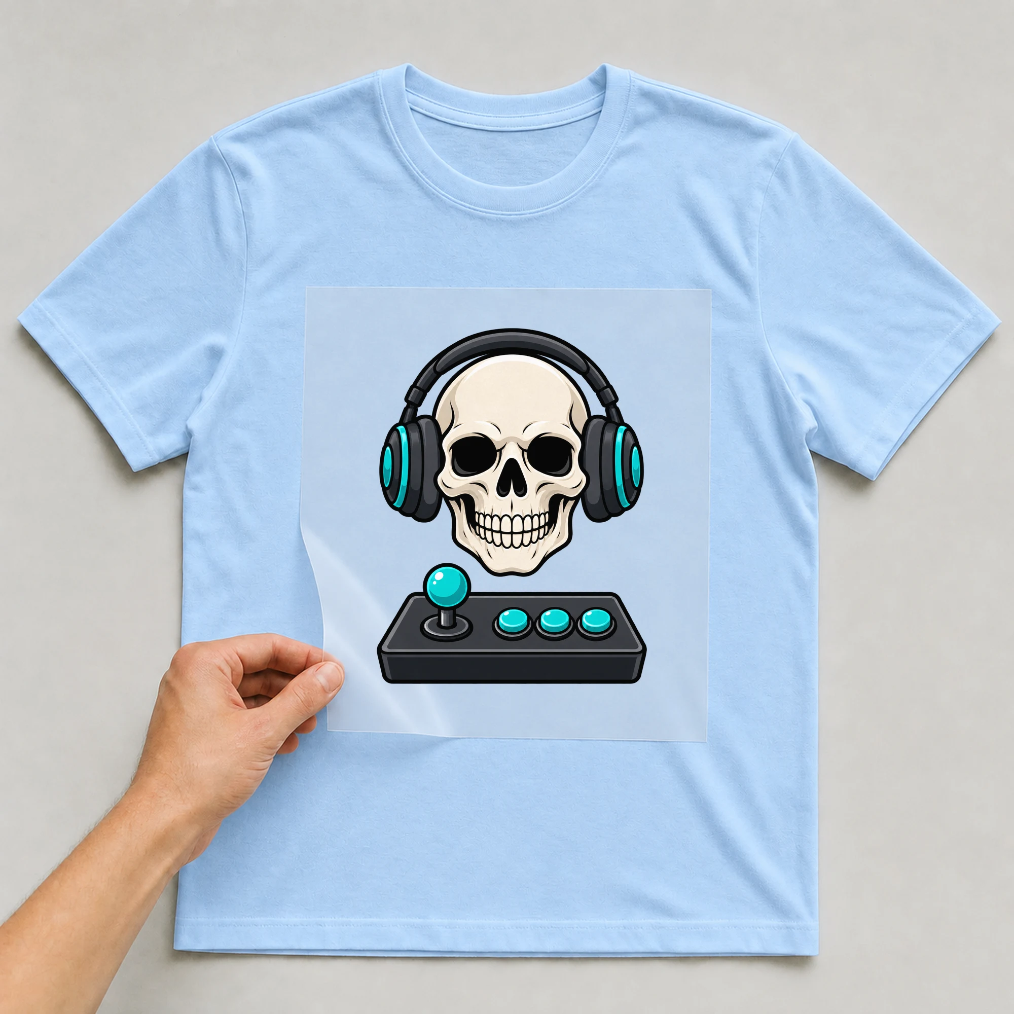 Bügelbild „Skull Gamers“ auf babyblauem T-Shirt, Folie wird aufgelegt