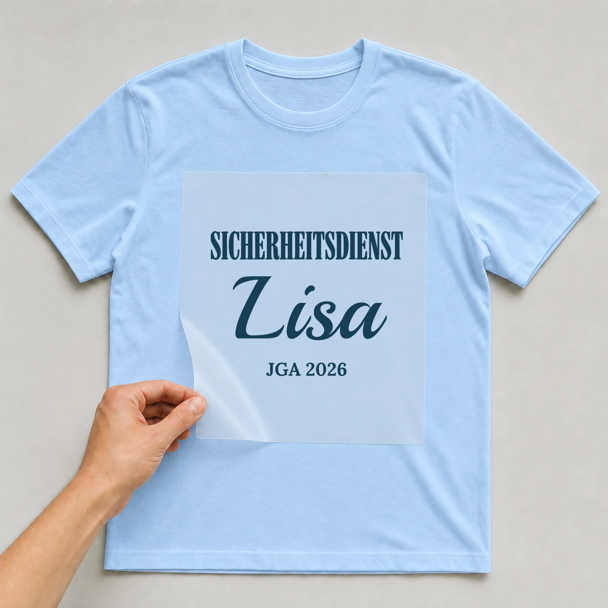 Bügelbild Sicherheitsdienst mit Name und Jahr auf hellblauem T-Shirt, Folie wird aufgelegt