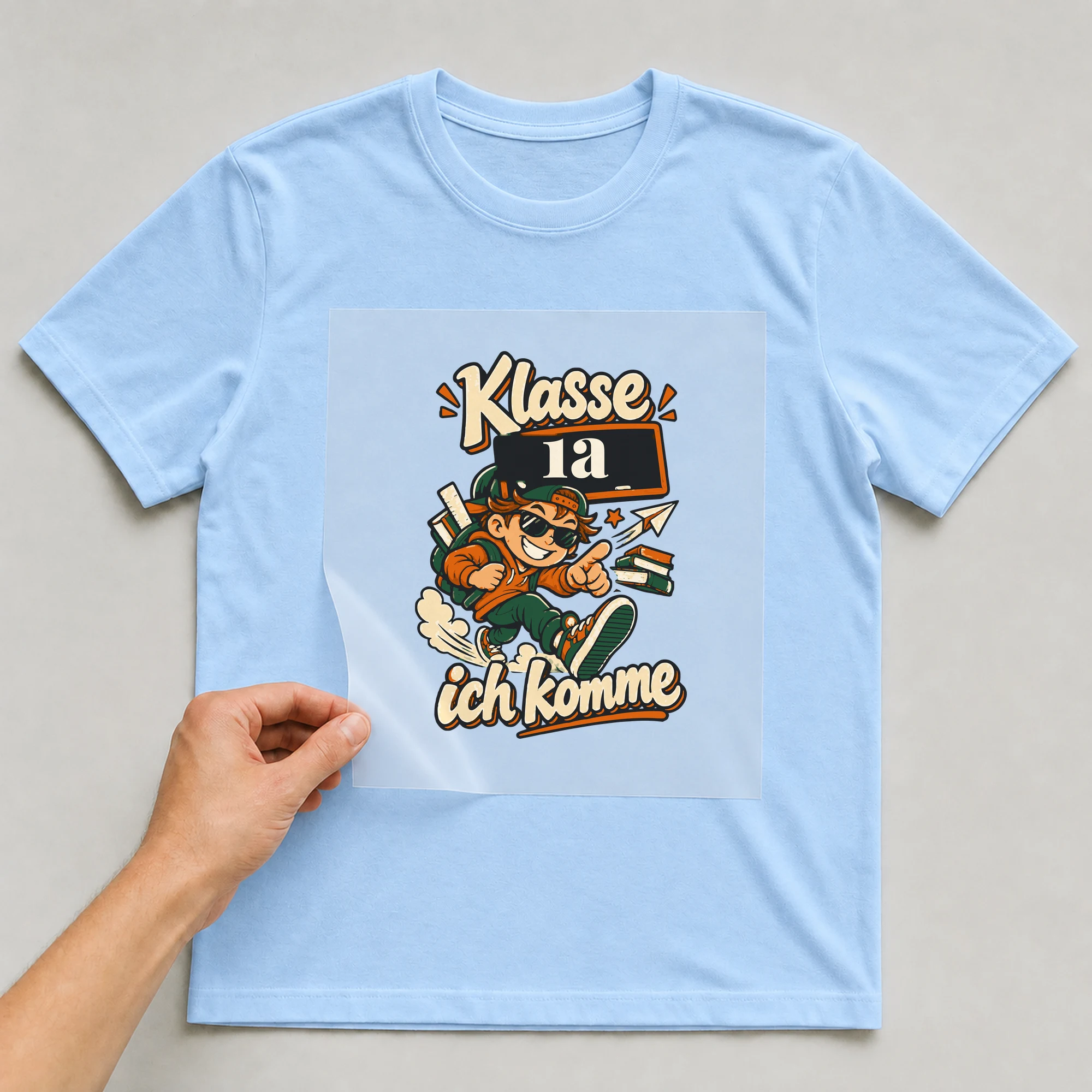 Bügelbild Klasse, ich komme mit Klasse auf hellblauem T-Shirt, Folie wird aufgelegt