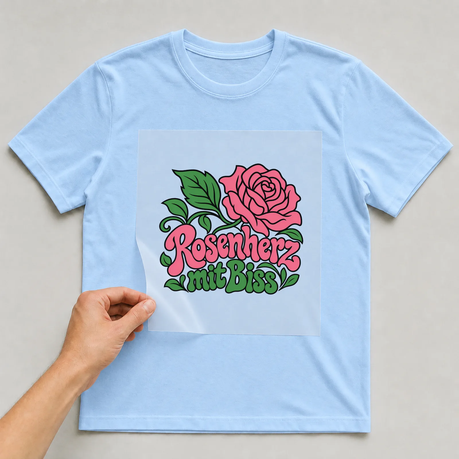 Bügelbild „Rosenherz mit Biss“ auf hellblauem T-Shirt, Folie wird aufgelegt