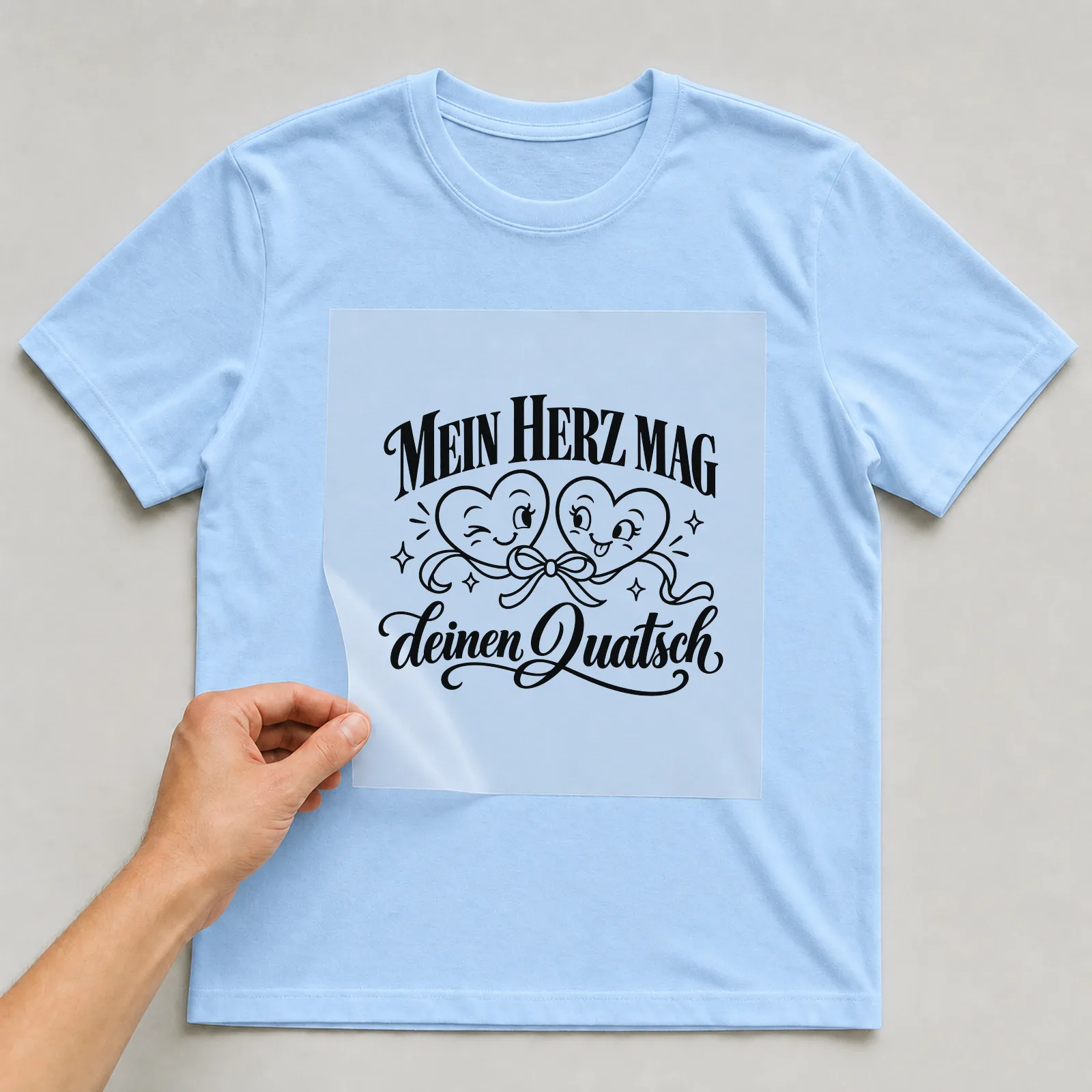 Bügelbild „Mein Herz mag deinen Quatsch“ auf hellblauem T-Shirt, Folie wird aufgelegt