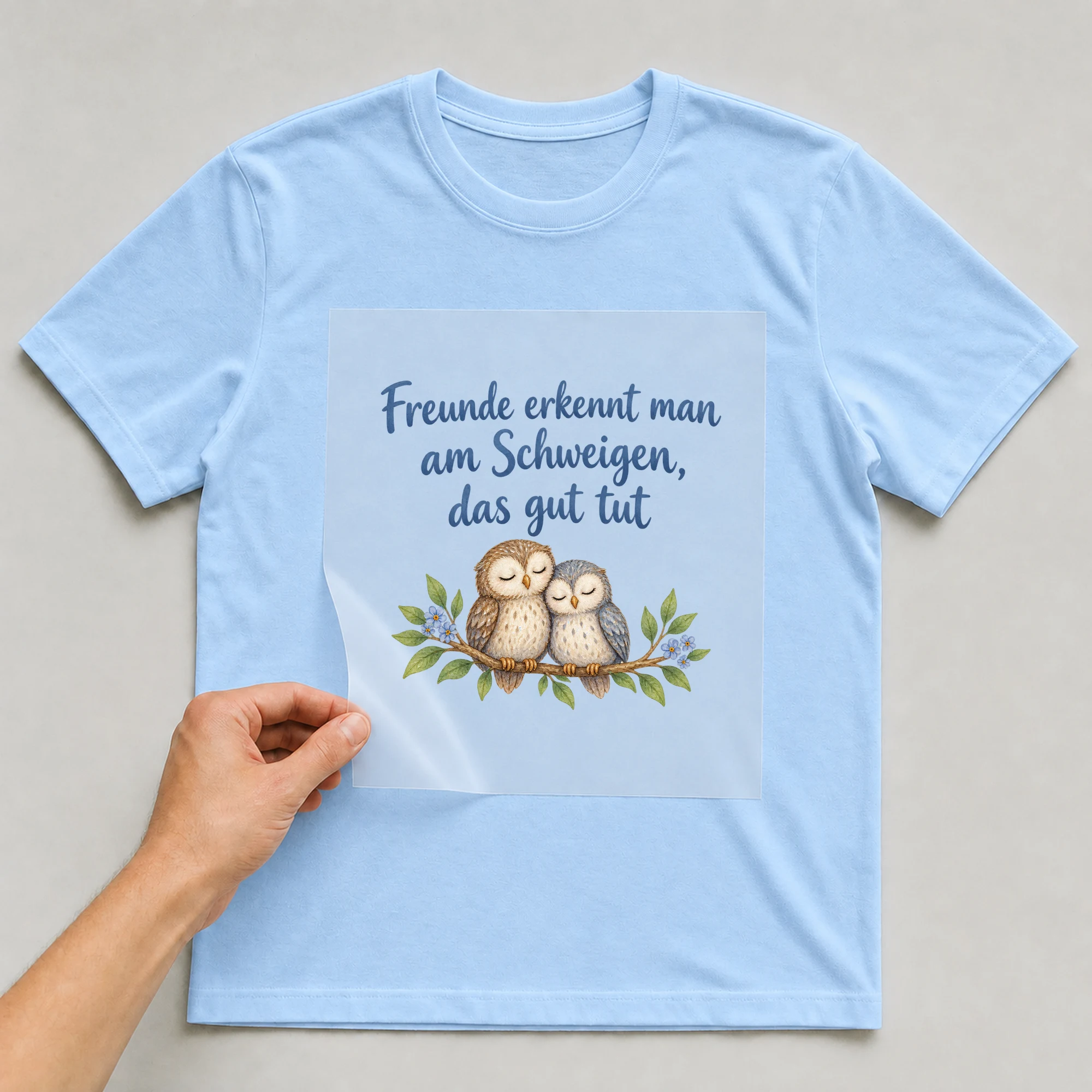 Bügelbild „Freunde erkennt man am Schweigen, das gut tut“ auf babyblauem T-Shirt, Folie wird aufgelegt