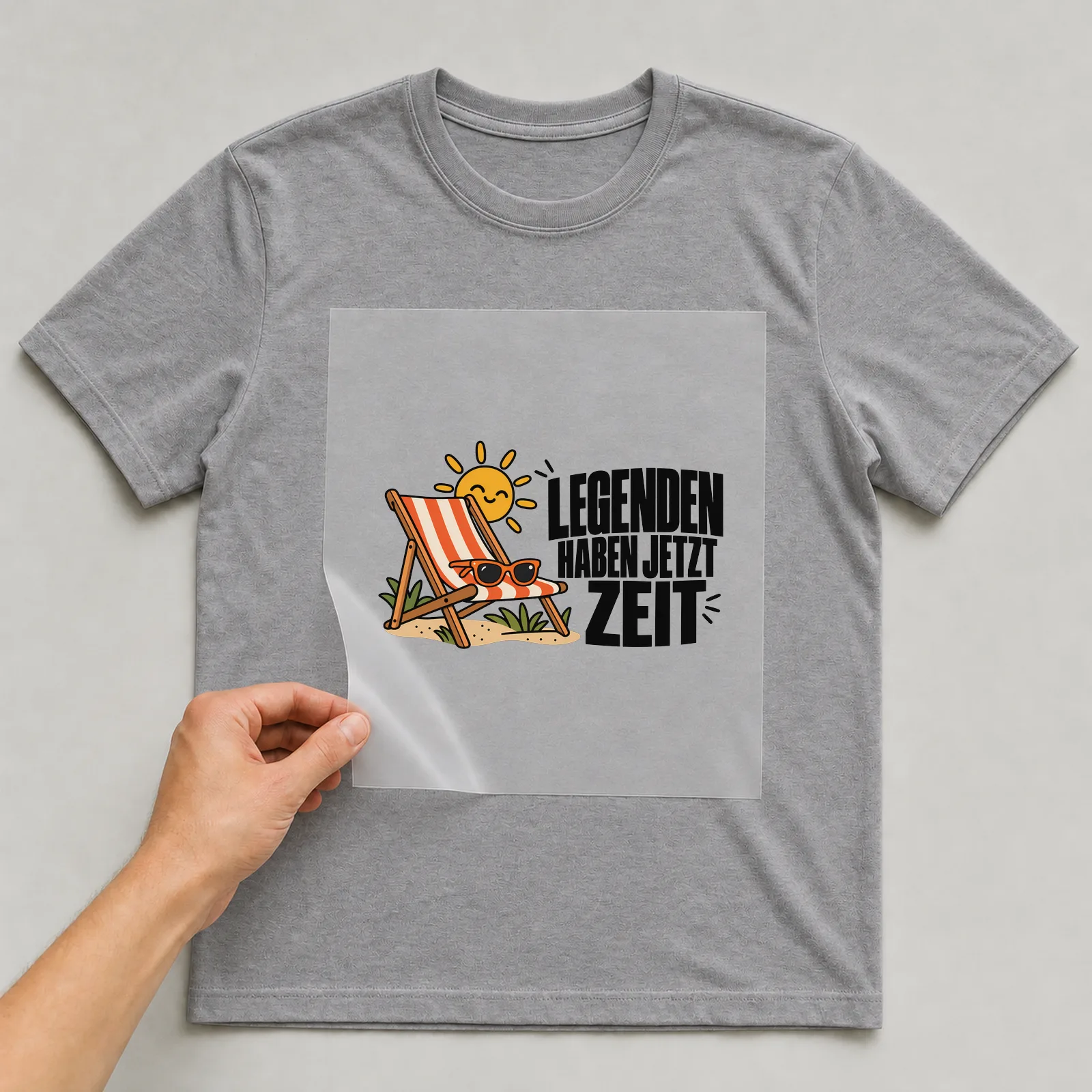 Bügelbild „Legenden haben jetzt Zeit“ auf grauem T-Shirt, Folie wird aufgelegt